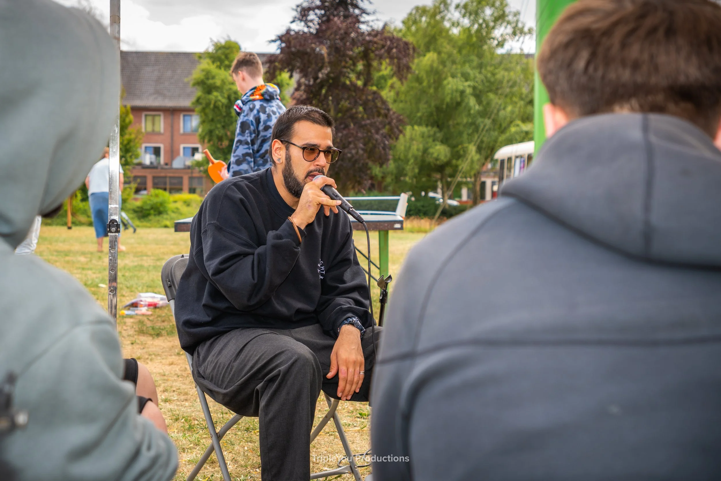 Een rapper, beatboxer, zanger, in het stadspark van stad torhout die les geeft aan jongeren hoe je kan leren beatboxen.