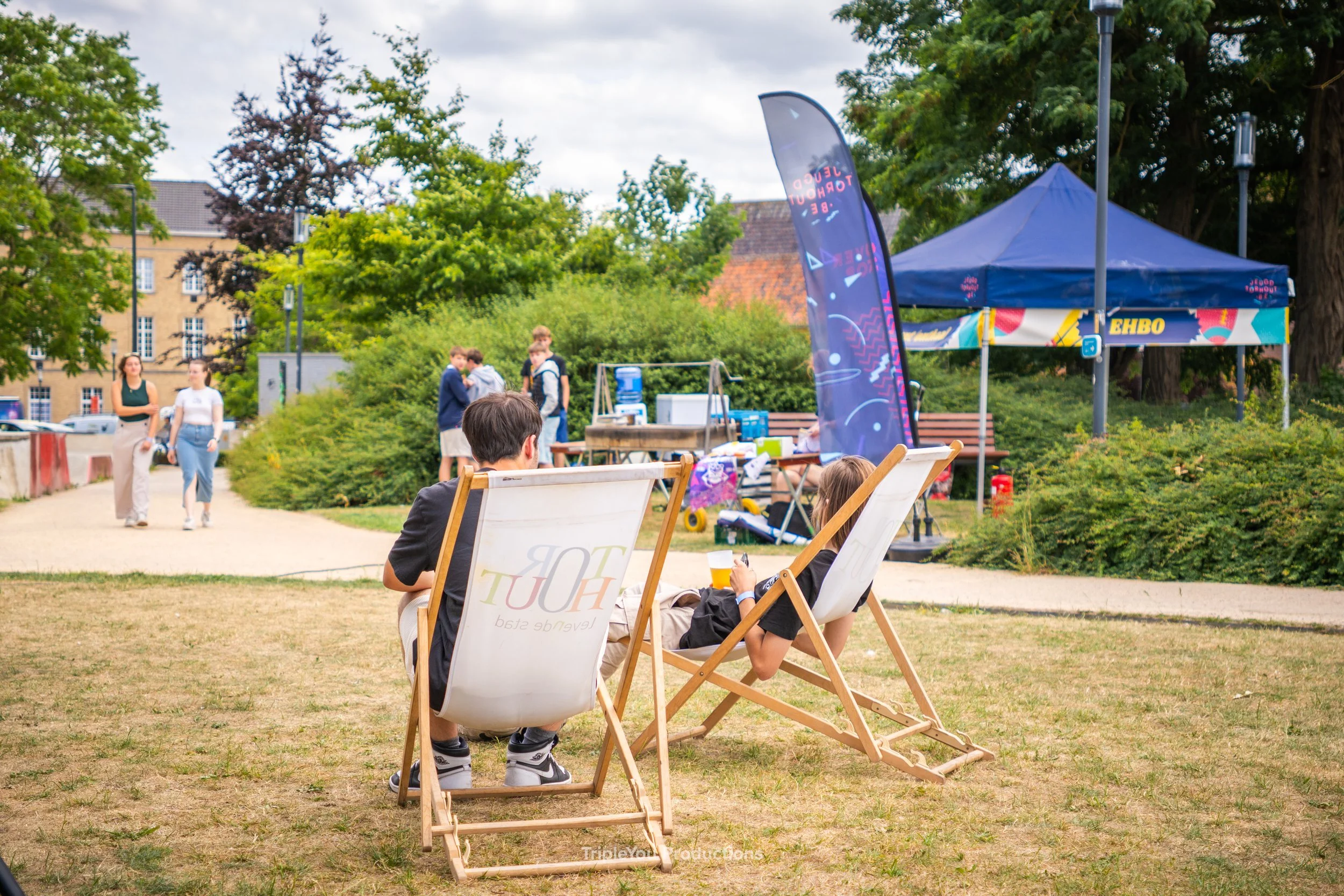 Twee mensen die in een strandstoeltje van Stad Torhout zitten in het gras van het stadspark achter het stadskantoor.