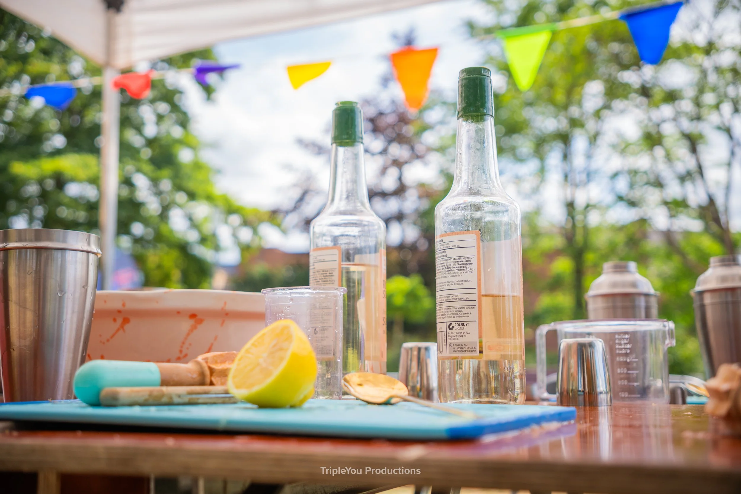 Een citroen, meetbekers, alcohol, een snijplank, vlaggetjes en een tentje. Een tafel met alle benodigdheden voor de workshop mocktails maken. 