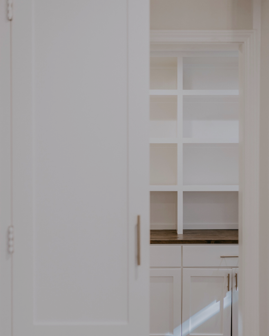 Part of a white cabinet with glass-paneled doors and gold handles, showing shelving inside.