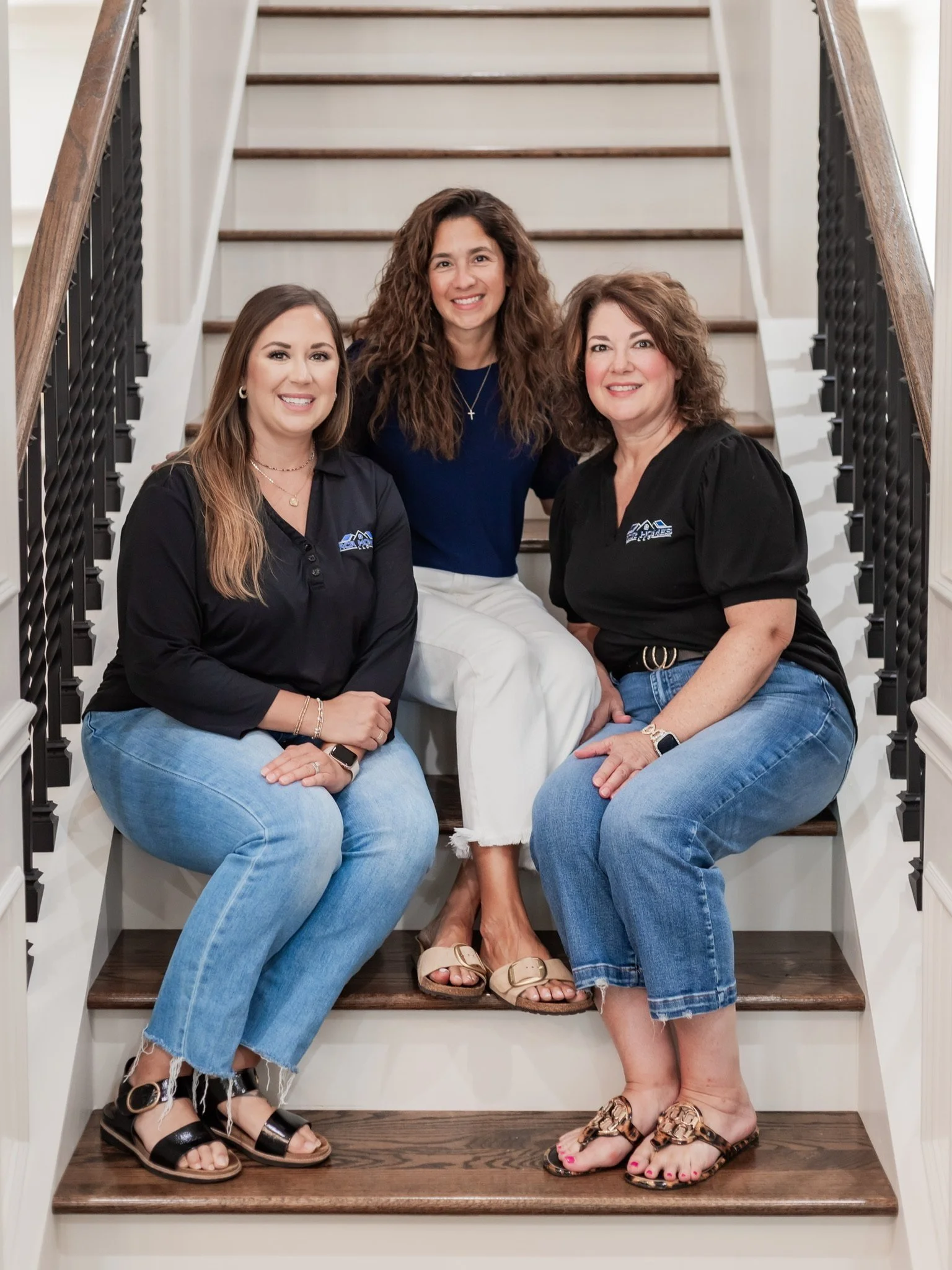 Three women sitting on a staircase, smiling at the camera.
