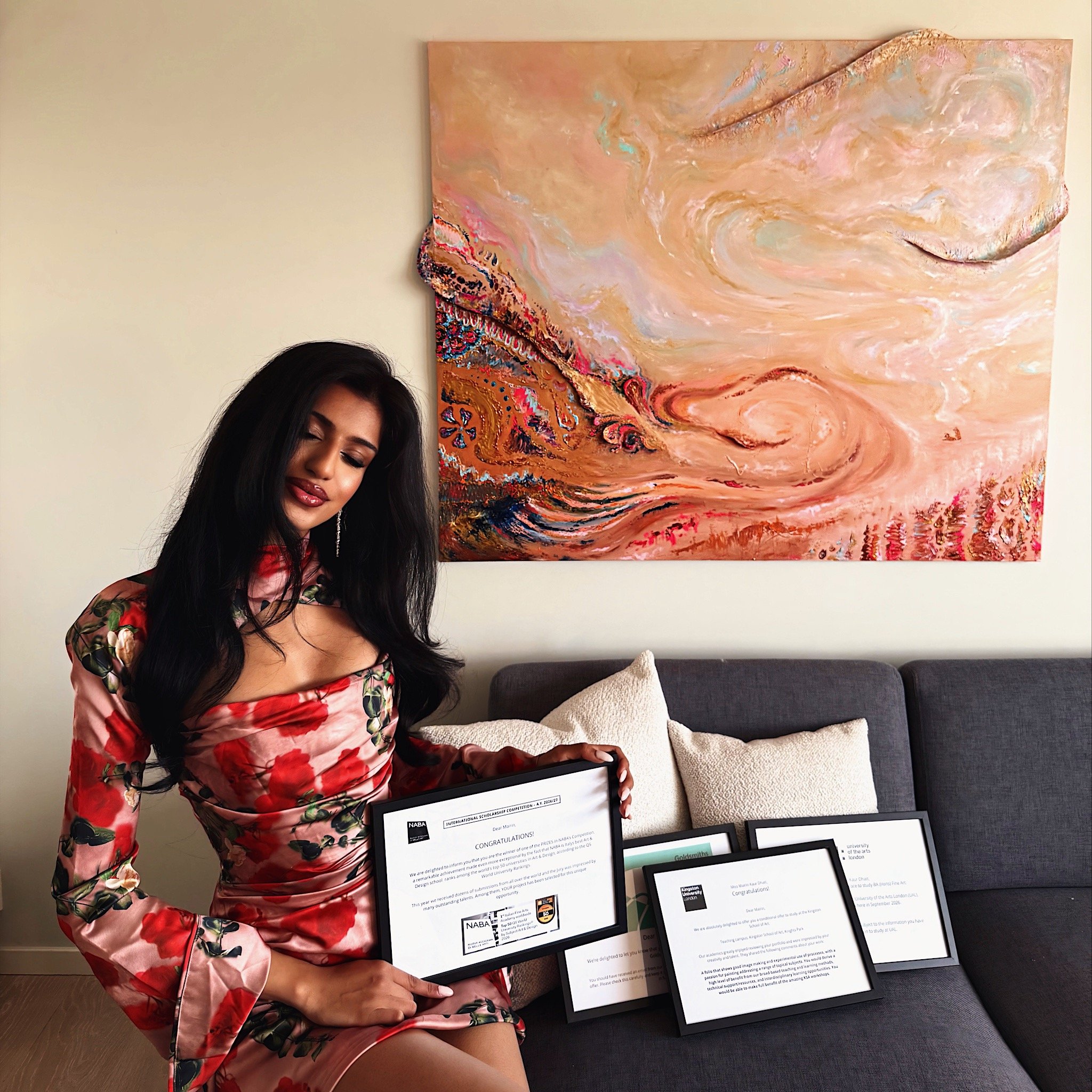 Mairin Kaur Dhatt med diplomer og utmerkelser fra en rekke prestisje universiteter med maleriet "Protection" bak seg.