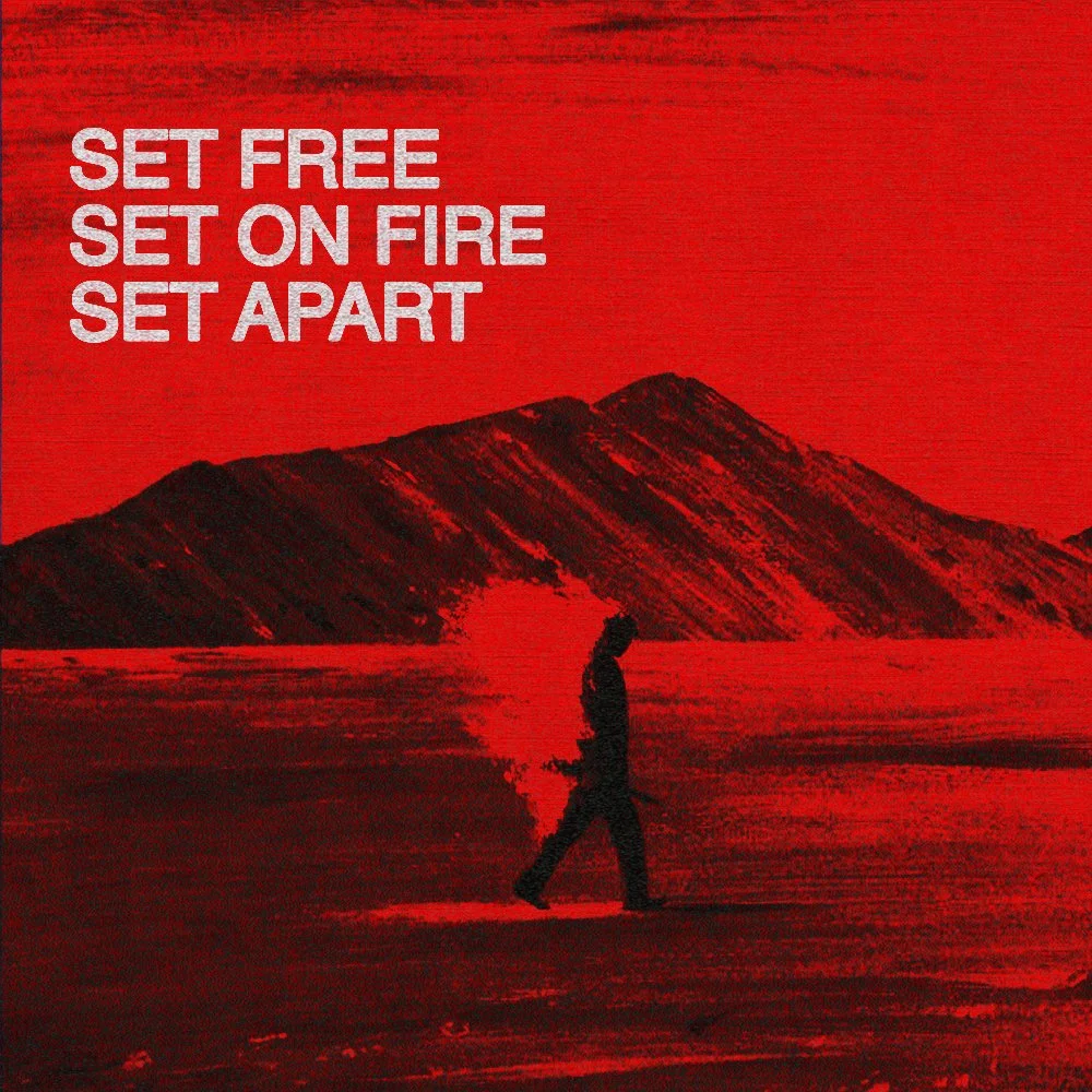 A person walking in a desert with a mountain in the background, surrounded by a red hue. Text in the upper left corner reads: 'Set Free, Set on Fire, Set Apart.'