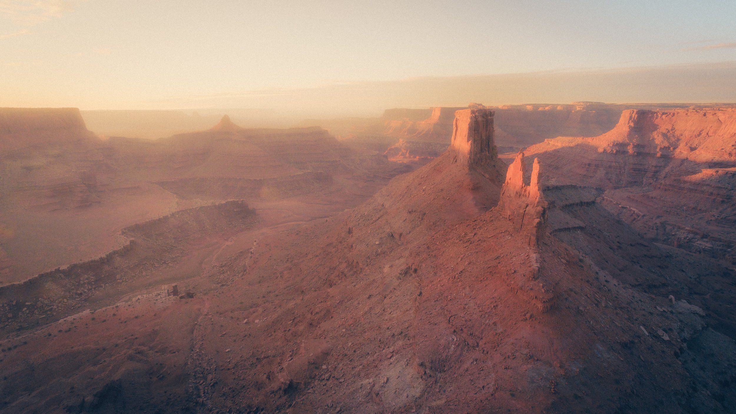 Scenic view of rugged, snow-capped mountains in a canyon with a valley and trees at the base, under a partly cloudy sky.