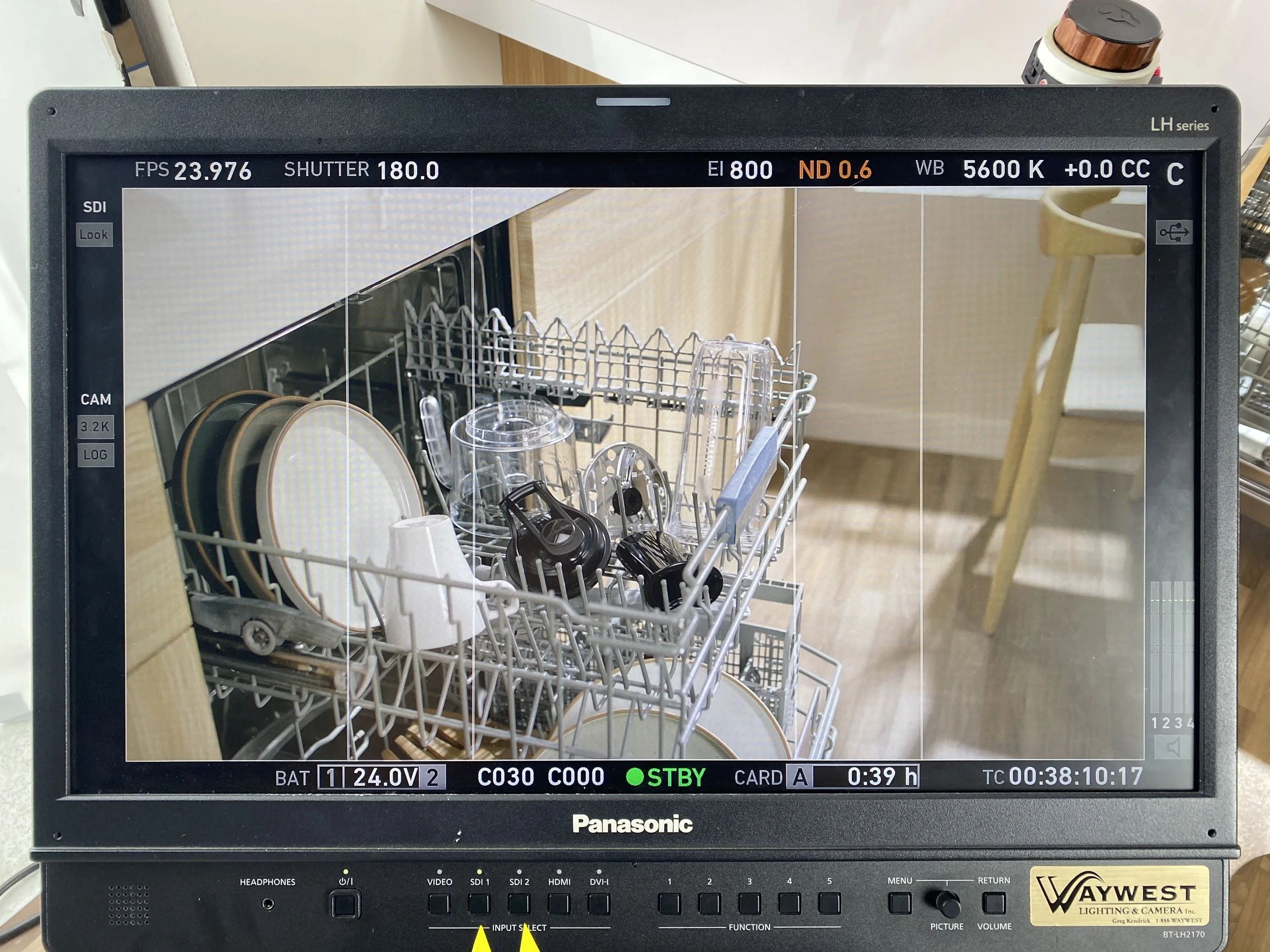 Dishwasher filled with clean dishes, including plates, cups, and utensils, viewed on a monitor screen.