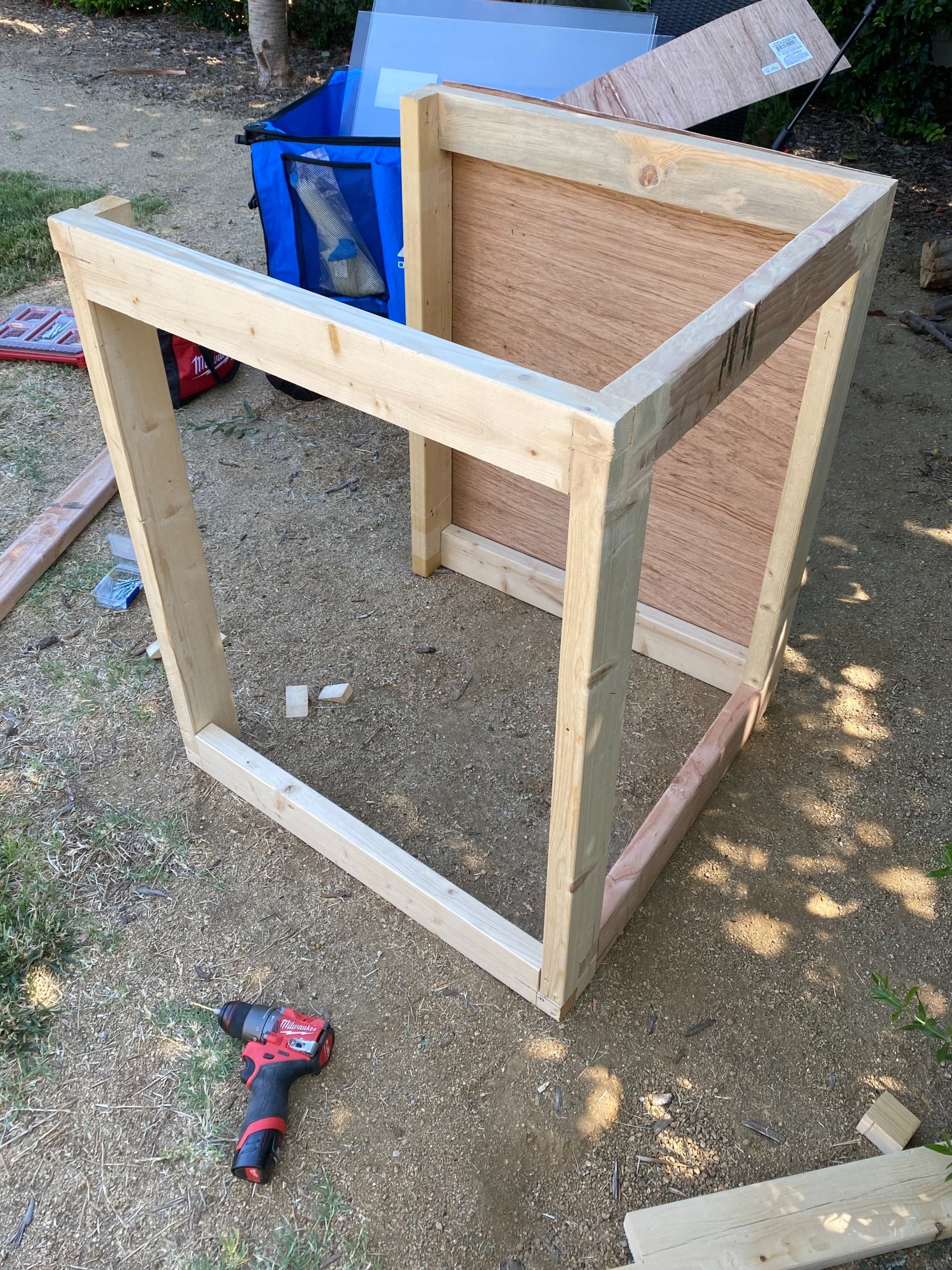 Wooden frame structure under construction outdoors with tools and materials nearby.
