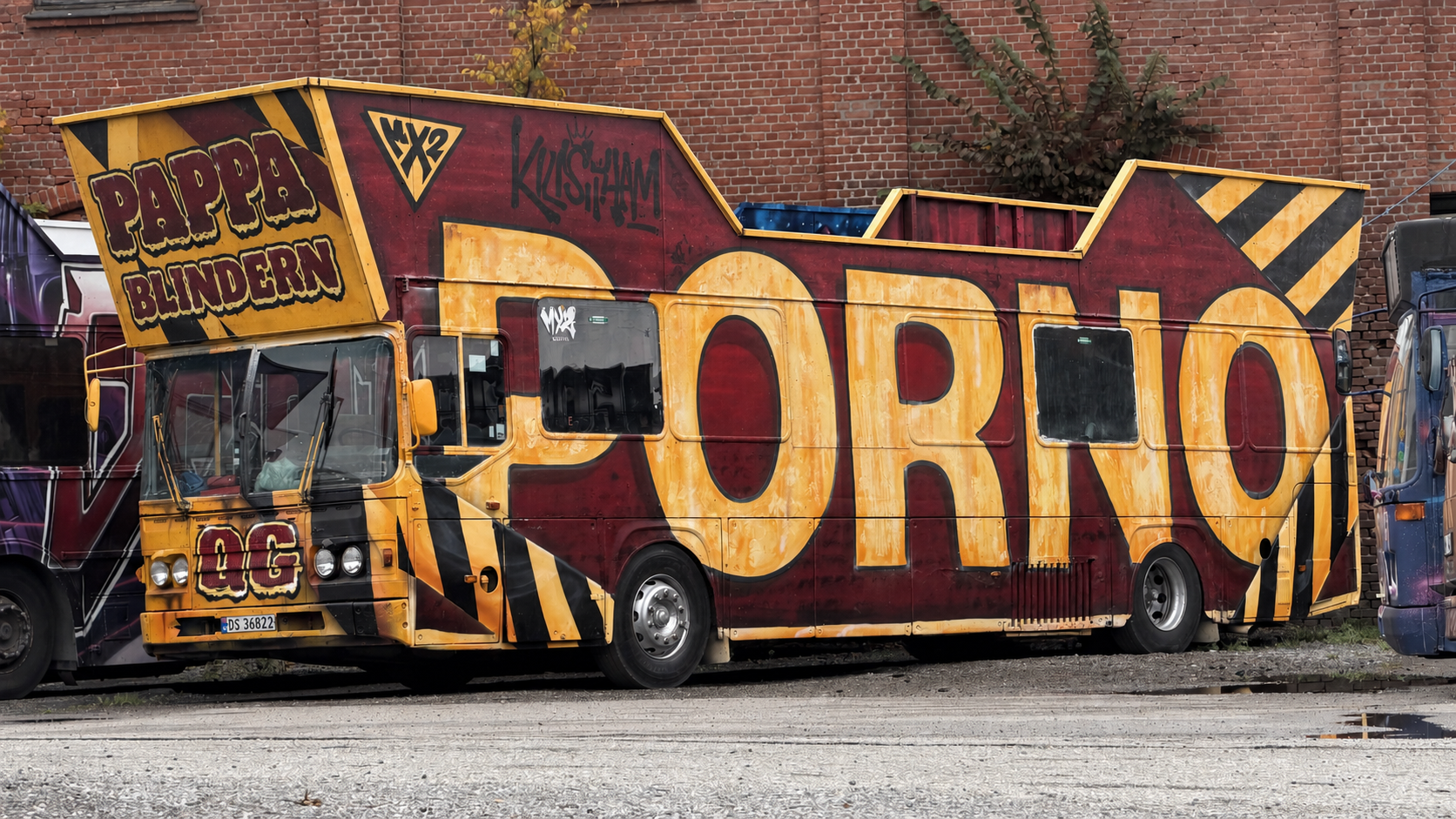 Graffitikledd partybuss ved murvegg.png