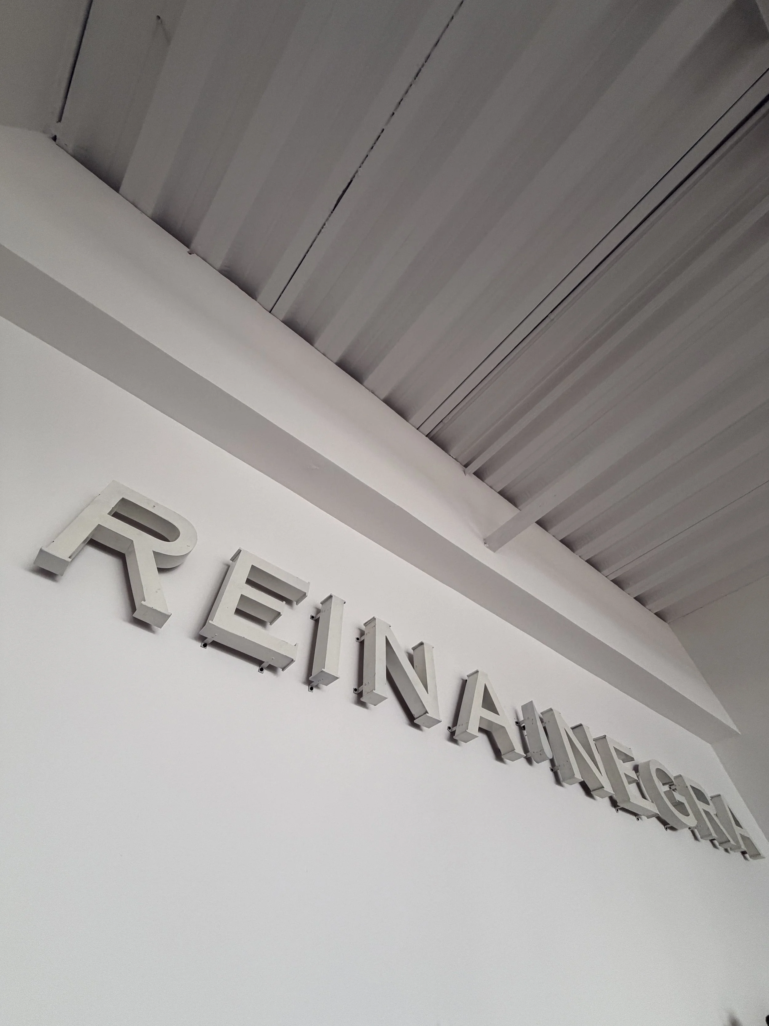 Vista del techo de un edificio con letras en relieve que dicen 'REINTEGRADORES' en una pared blanca.