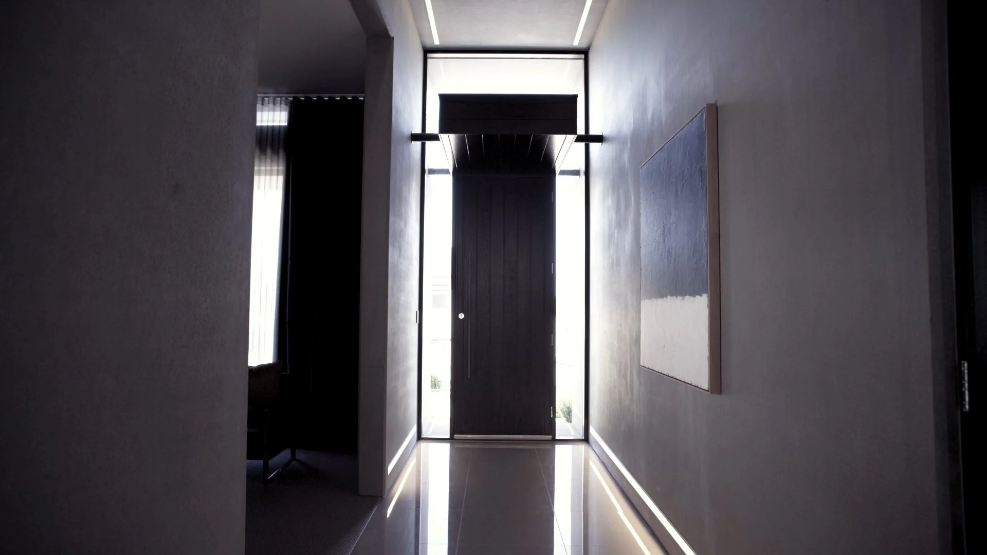Modern hallway with large glass front door and natural light coming in, with artwork on the right wall.