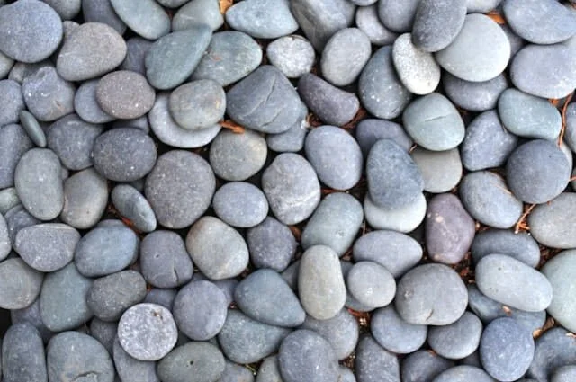 Smooth river rocks in soft, muted tones, evoking a sense of stillness and being settled.