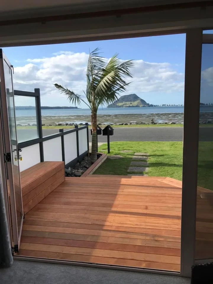 Custom-built timber deck with ocean view and integrated bench seating by Capital G Construction and CGC Property Solutions in Tauranga