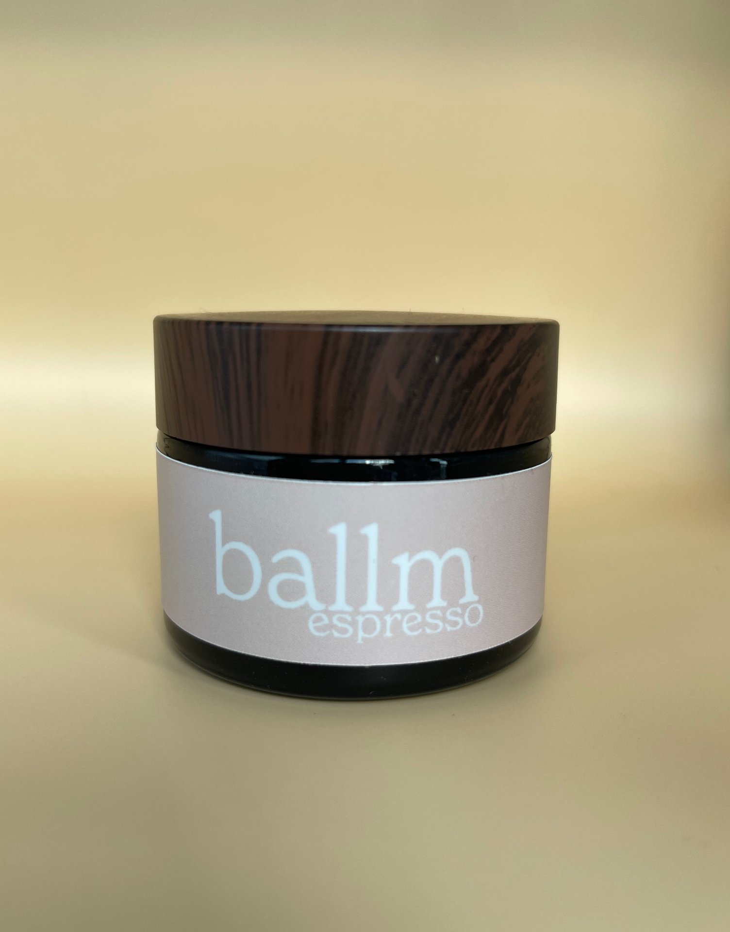 A small jar of balm espresso on a light-colored surface with a plain, light-colored background.