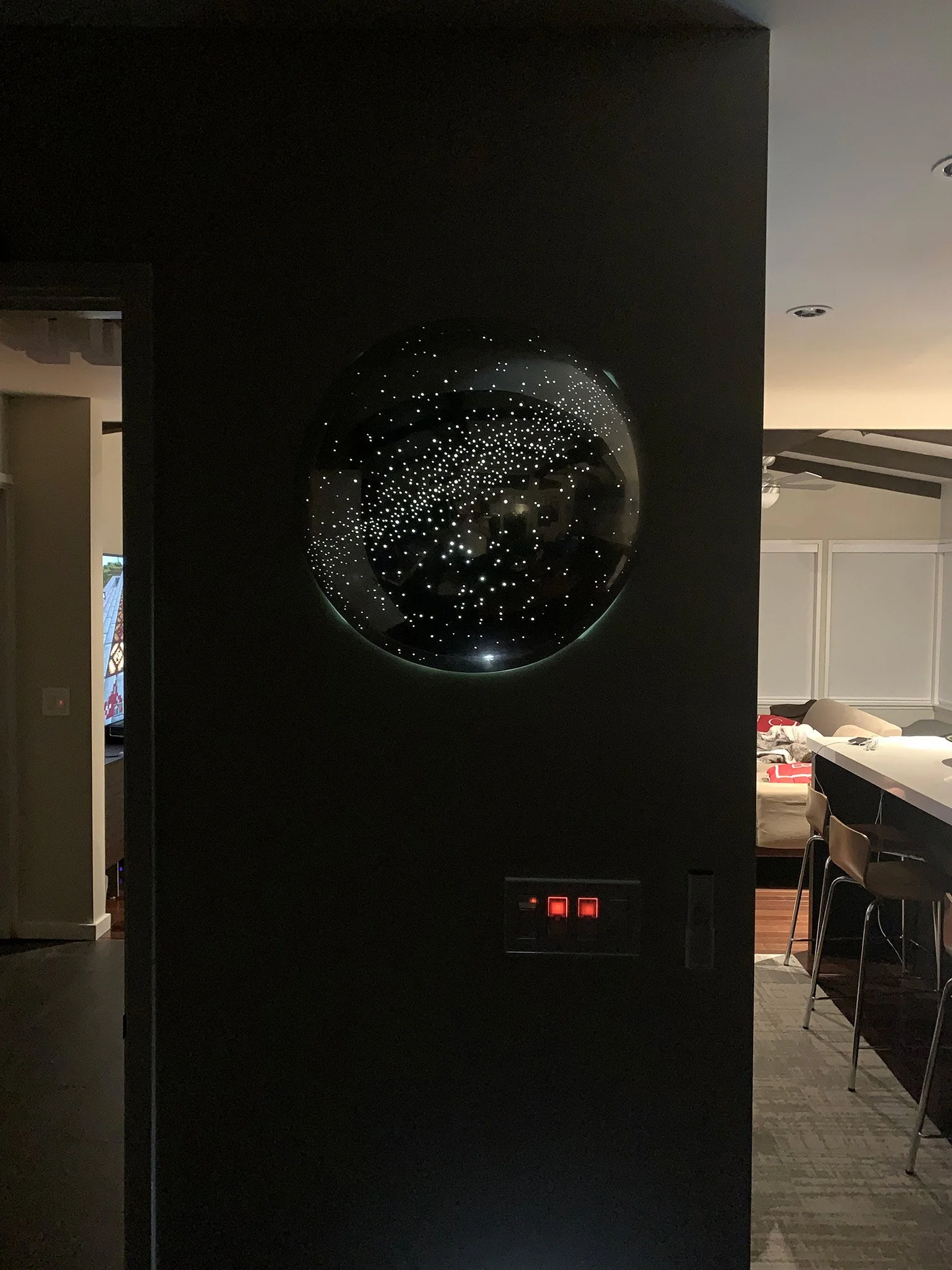 A spherical galaxy-themed mirror reflecting the starry sky and interior furniture inside a dark room.