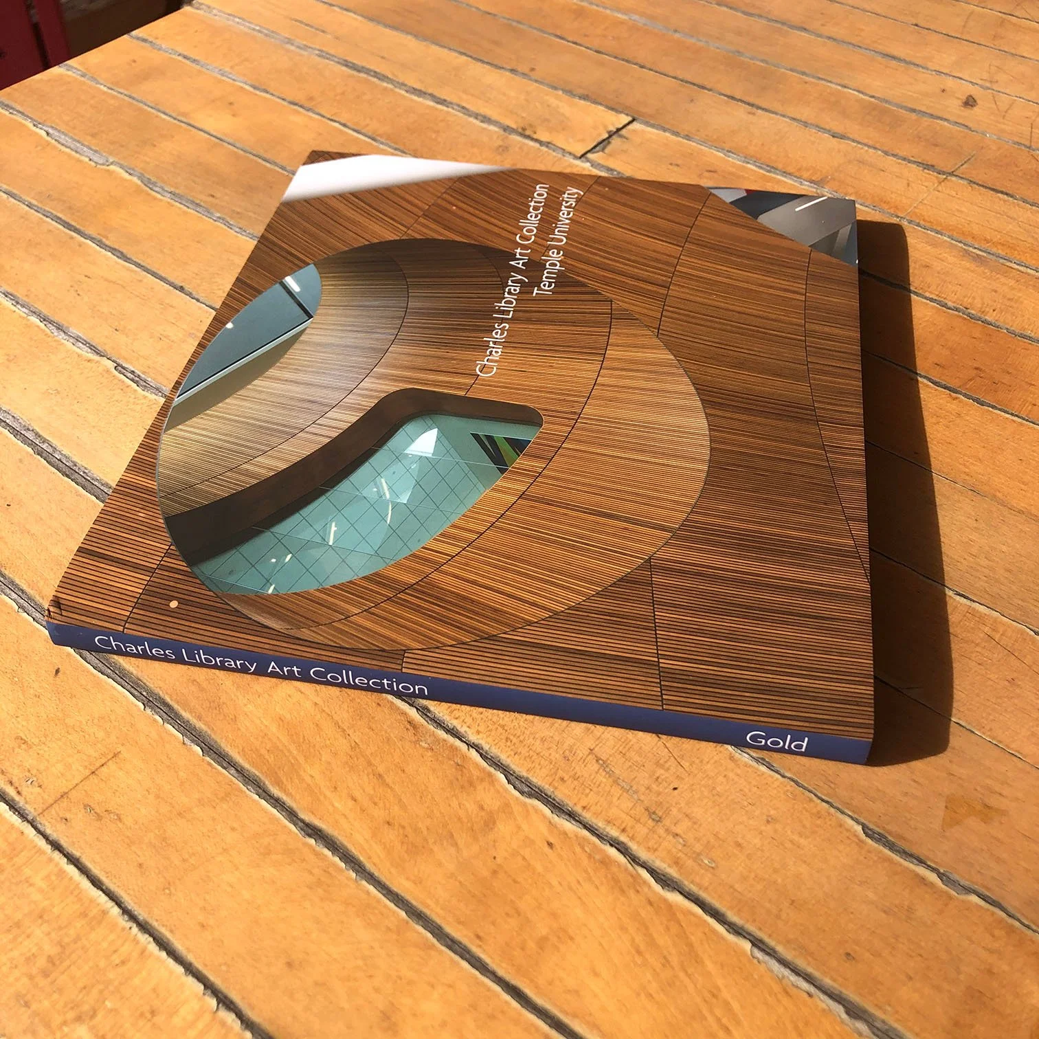 A book titled 'Charles Library Art Collection' resting on a wooden surface, featuring a modern architectural photograph on its cover.