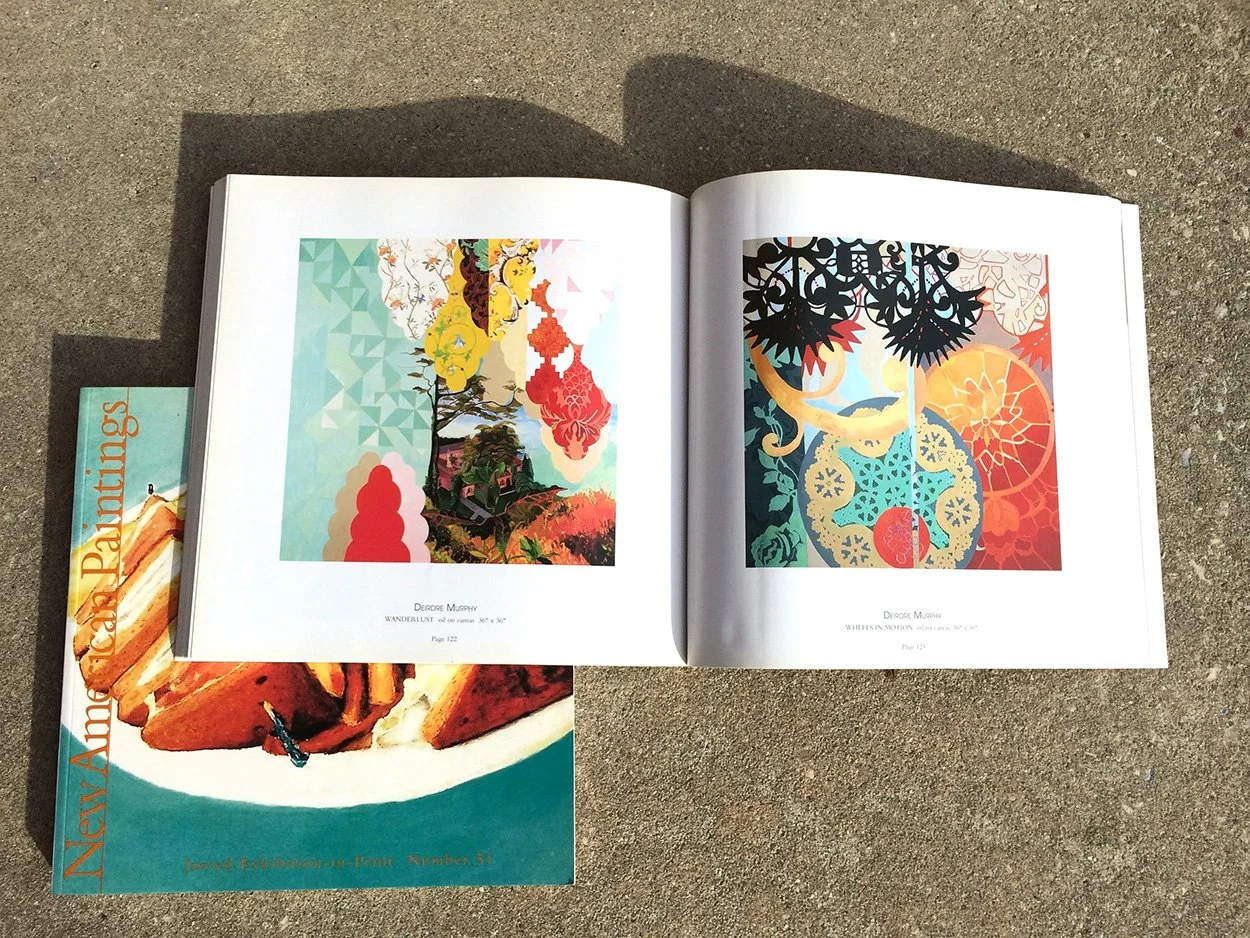 Open art book displaying colorful abstract paintings on pages, placed on concrete ground with a magazine titled "New American Paintings" partially underneath.