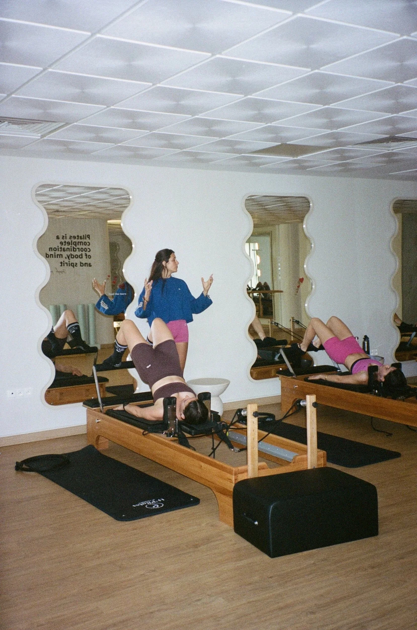 Cours de Pilates Reformer en petit groupe, avec une professeure guidant les participantes dans un studio lumineux et intimiste.