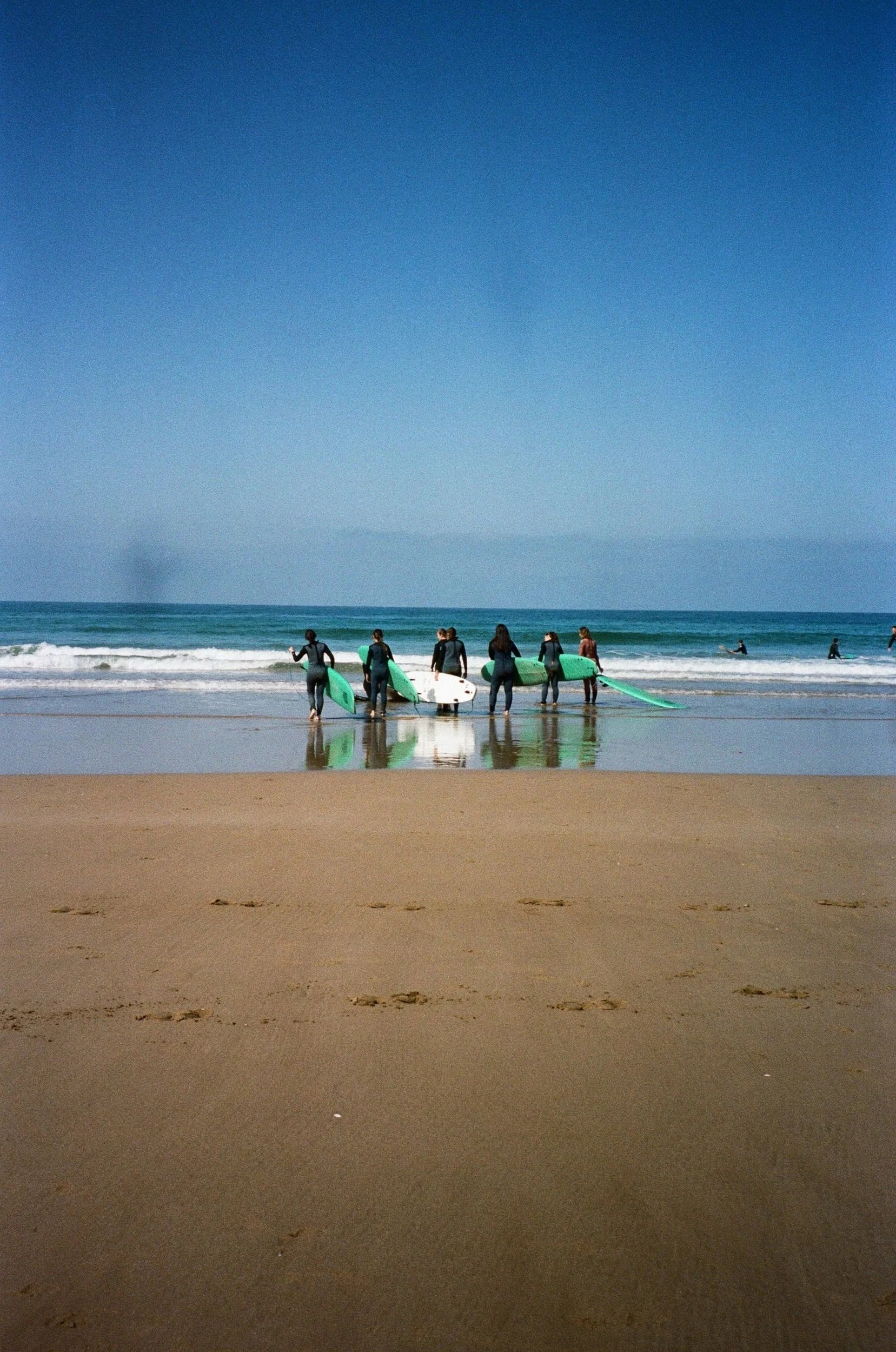 Groupe de surfeurs avec des planches de surf sur la plage, en direction de la mer calme par une journée ensoleillée.