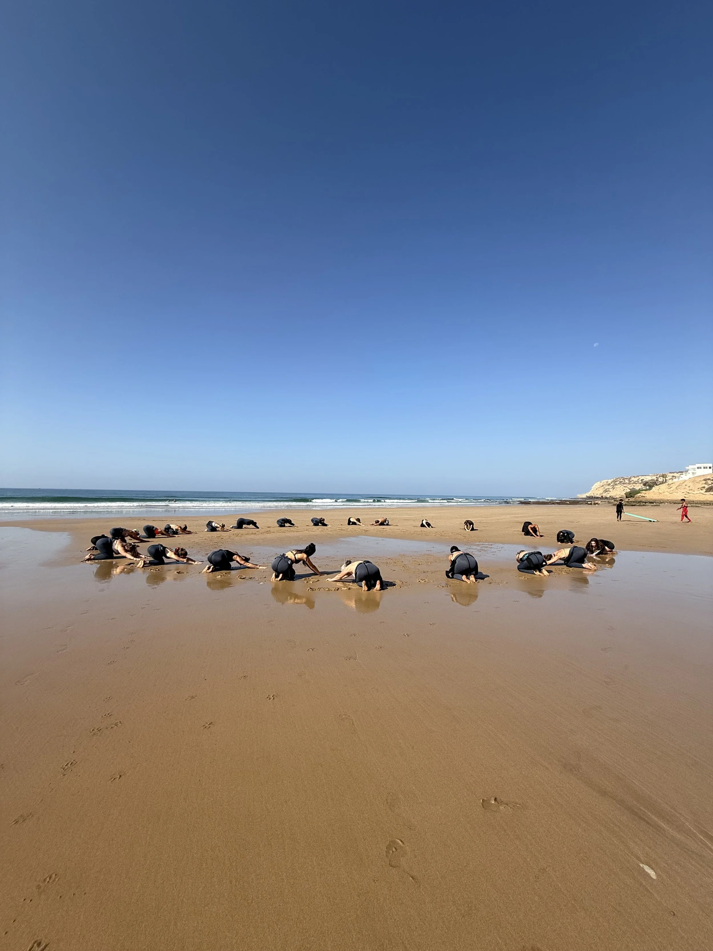 Echauffement du groupe de retraite sur la plage à Tamraght avant de surfer.