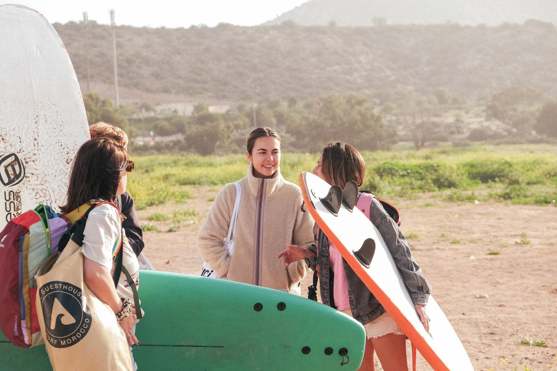 Groupe de participantes avec leurs planches de surf, partageant un moment convivial avant une session au soleil dans la région de Taghazout.