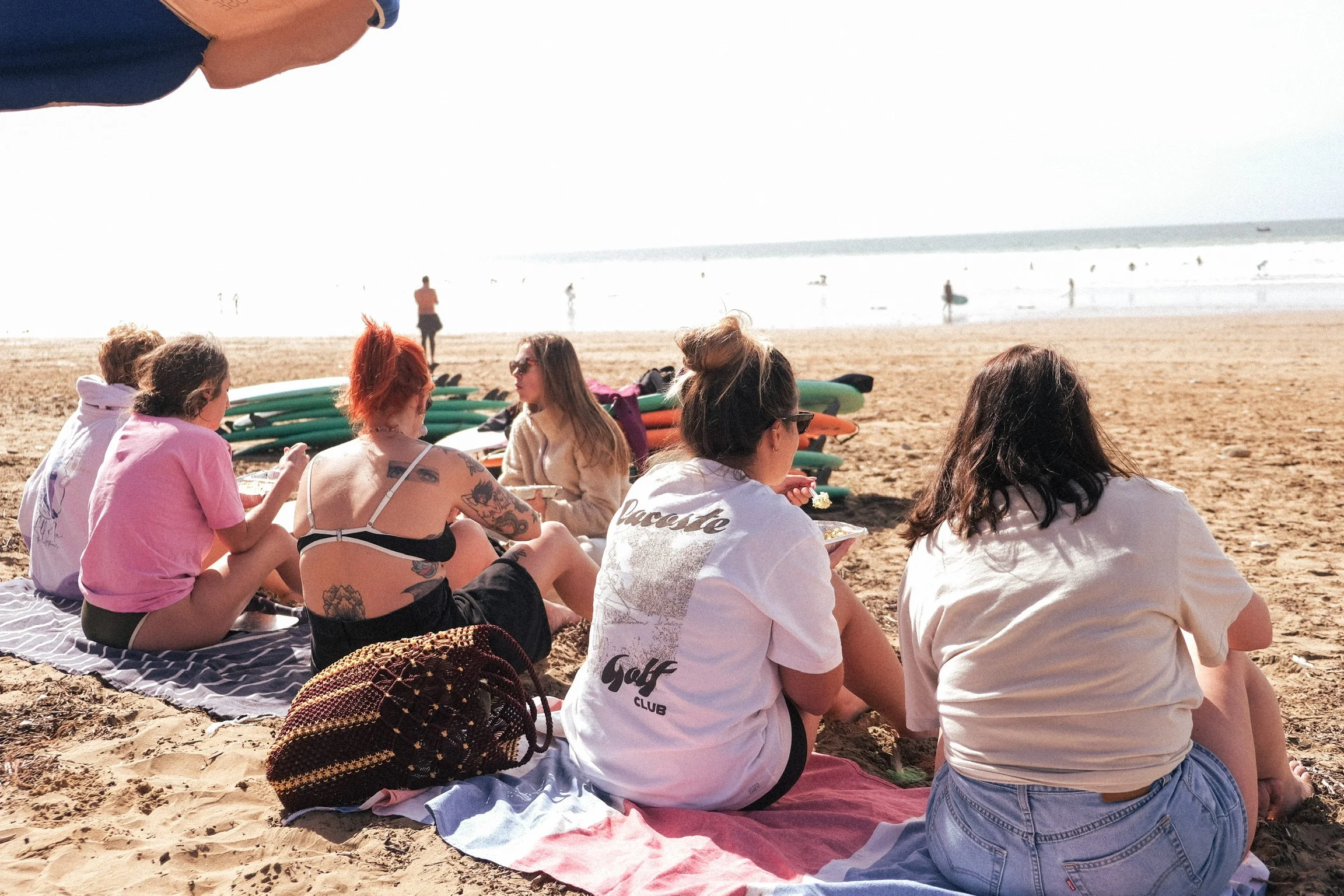 Moment convivial sur la plage après une session de surf, entre déjeuner au soleil, échanges et détente face à l’océan.