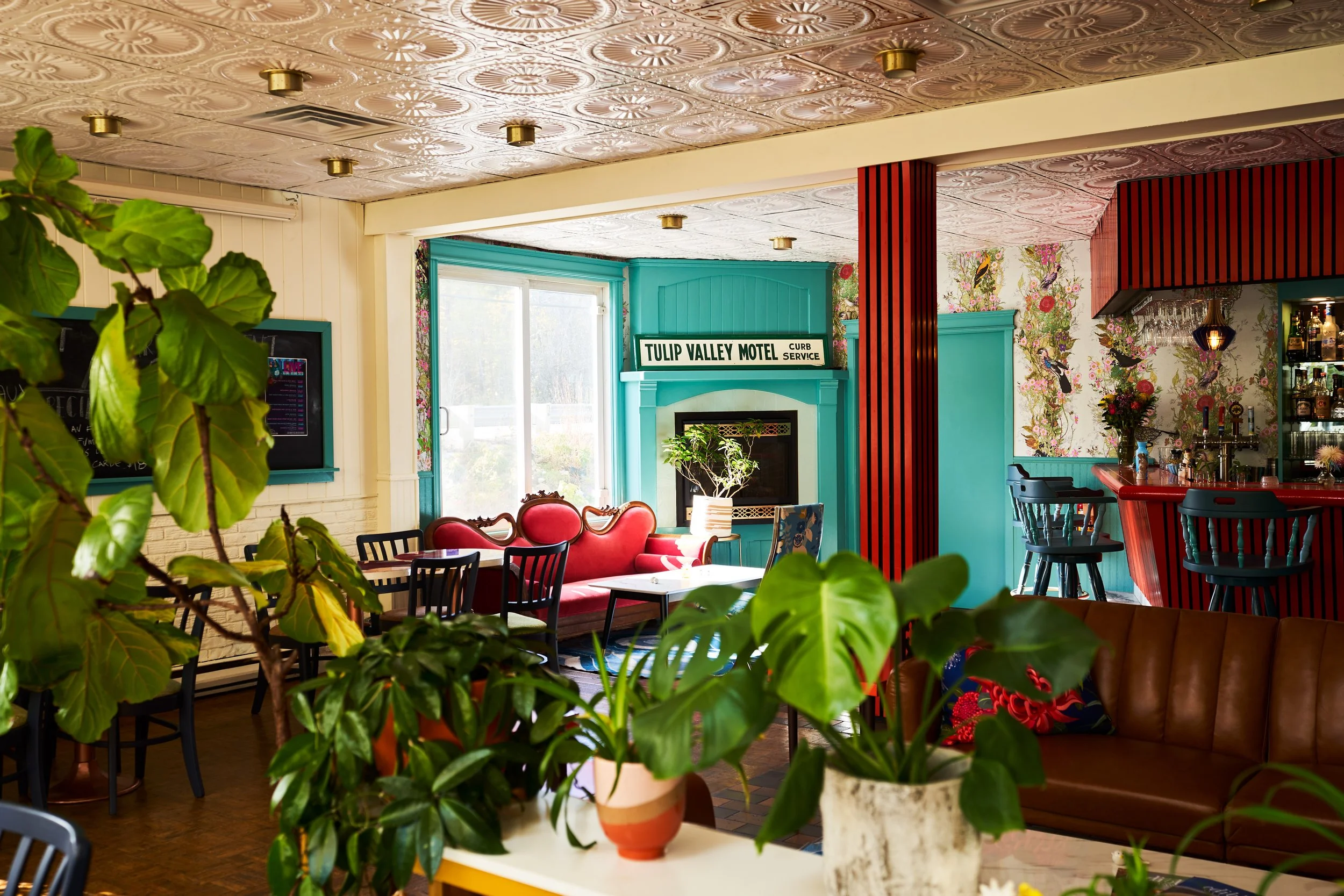 Interior of Motel Chelsea with tropical plants in pots, a red velvet sofa, bar. Photographed by Gumption Studio, Ottawa interior photographer. 