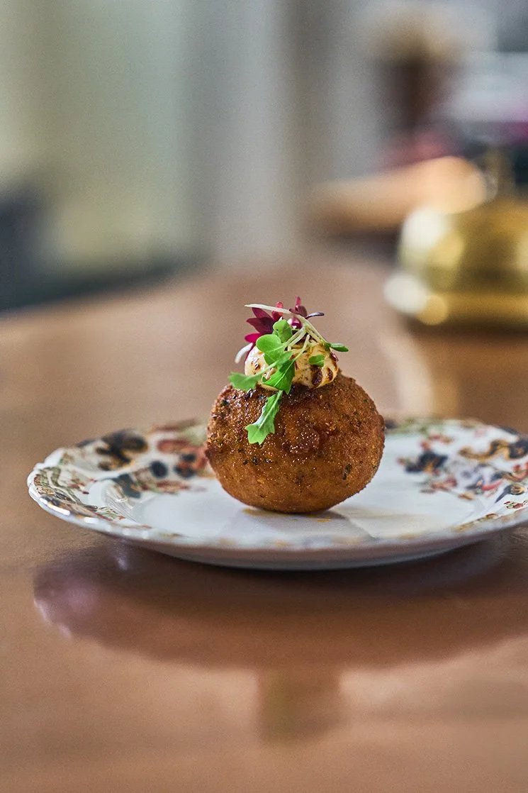 Arancini by garnished Afro Snacks garnished with microgreens on a decorative plate at the Girl Dinner Event. Photographed by Gumption Studio, Ottawa event photographer.