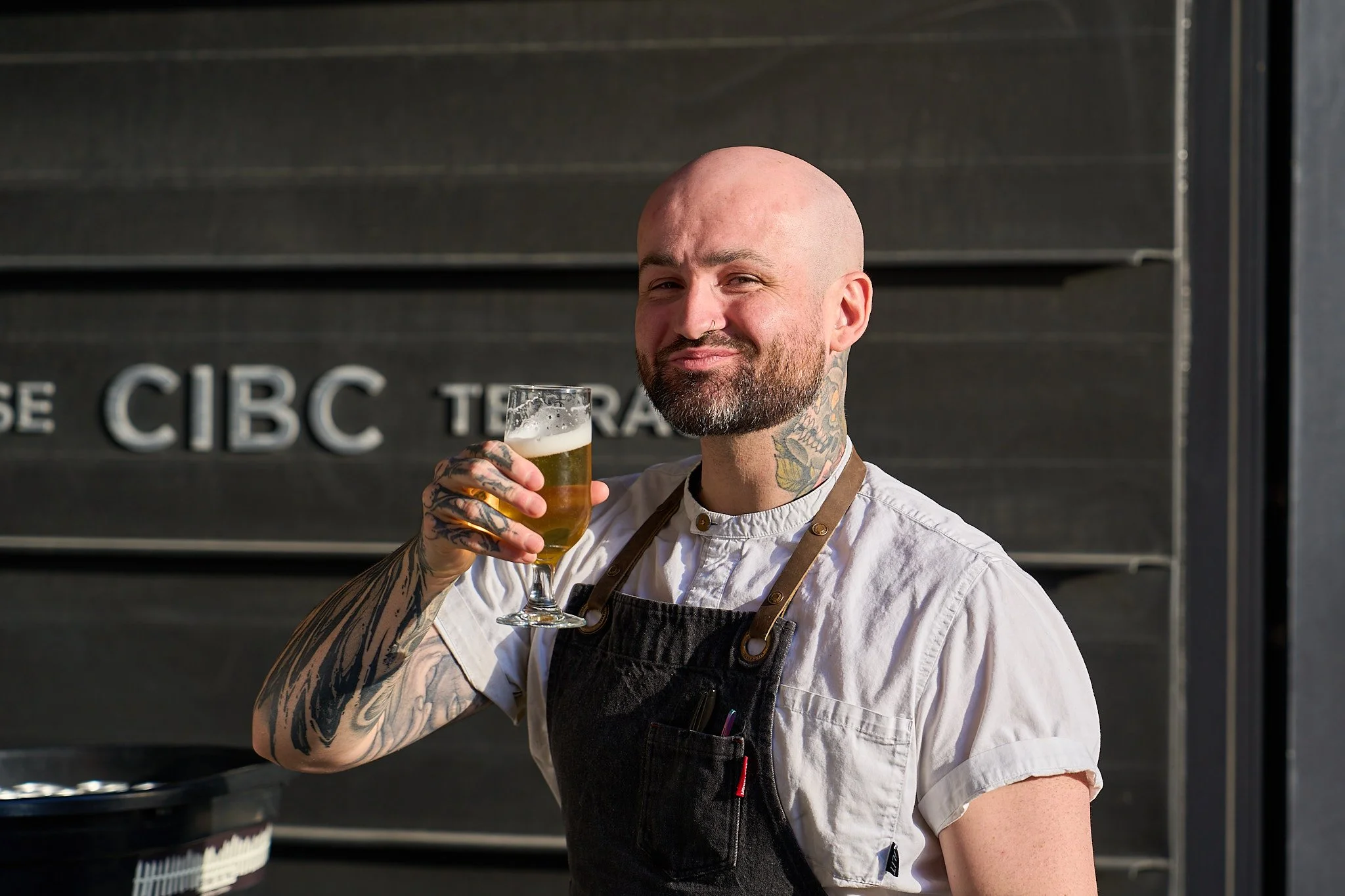 Chef Cameron McGihon holding a glass of beer at Harvest: A Feast of Fall. Photographed by Gumption Studio, Ottawa event photographer.
