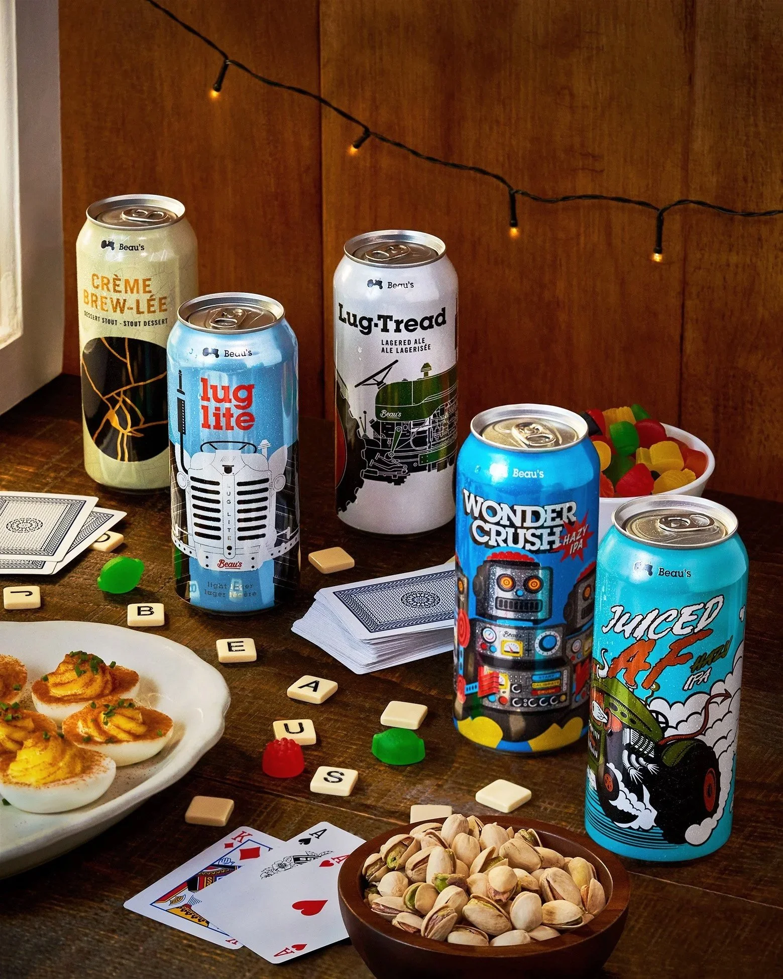 A table with various cans of beer Beau's beer, playing cards, pistachios, and some desserts. Taken for their Christmas Advertisement Photographed by Gumption Studio, Ottawa commercial beverage photographer.
