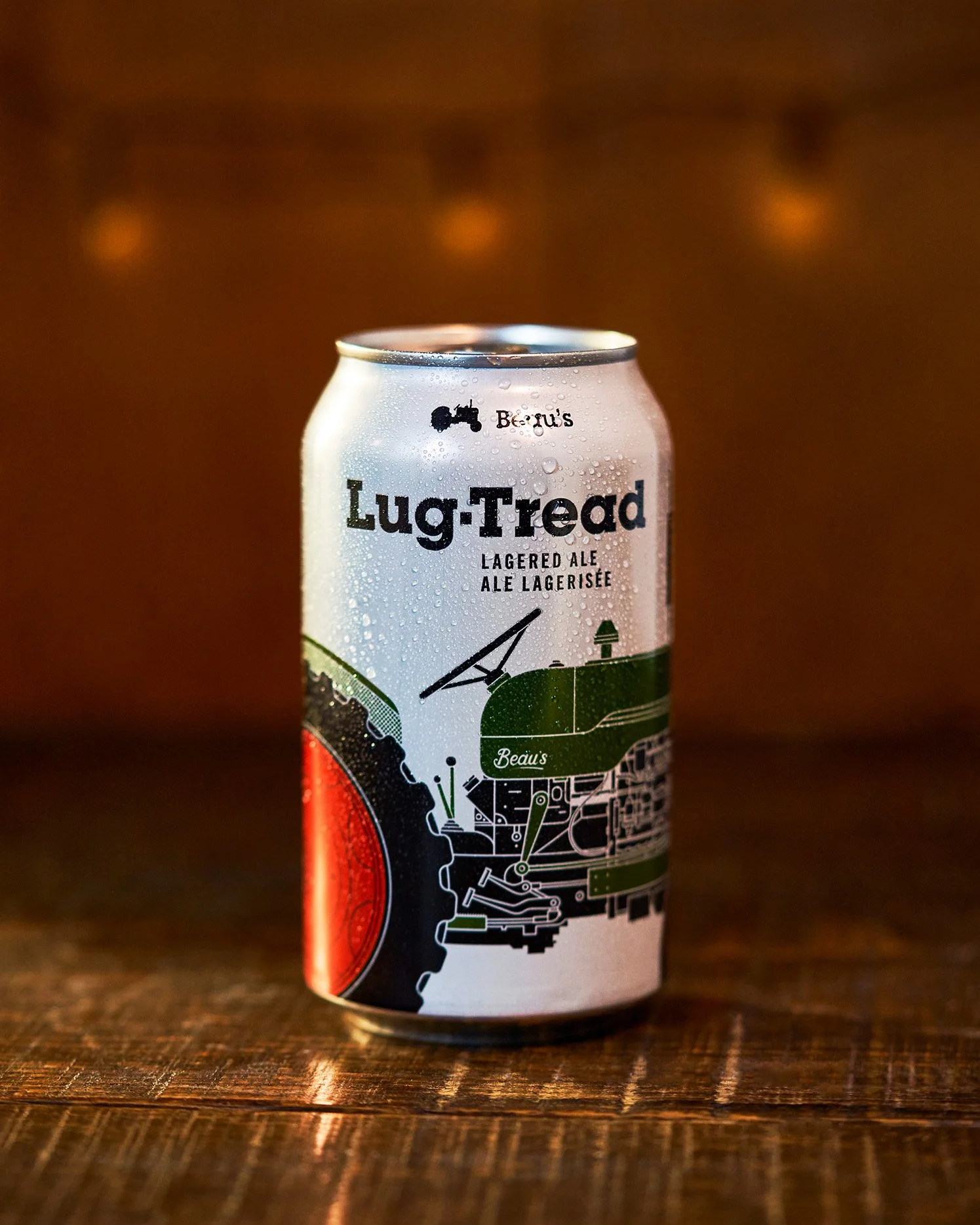 Close-up of a can of Beau's Lug-Tread beer on a wooden surface with a blurred warm background. Photographed by Gumption Studio, Ottawa commercial beverage photographer.