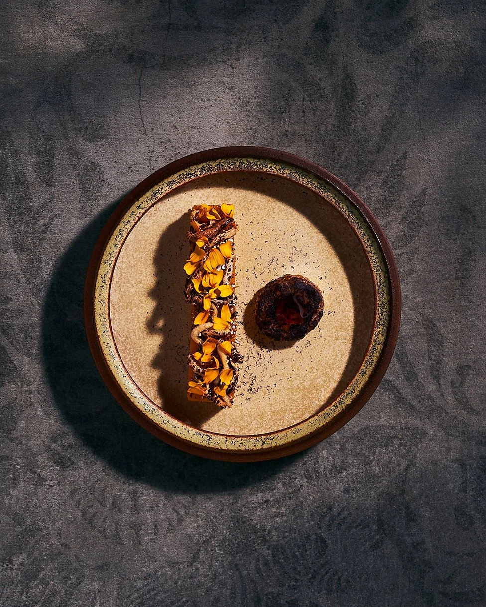 A squash dish by Justin Champagne-Lagarde on a brown ceramic plate, garnished with yellow flower petals. Photographed for the Perch Cookbook by Gumption Studio, Ottawa Cookbook photographer.