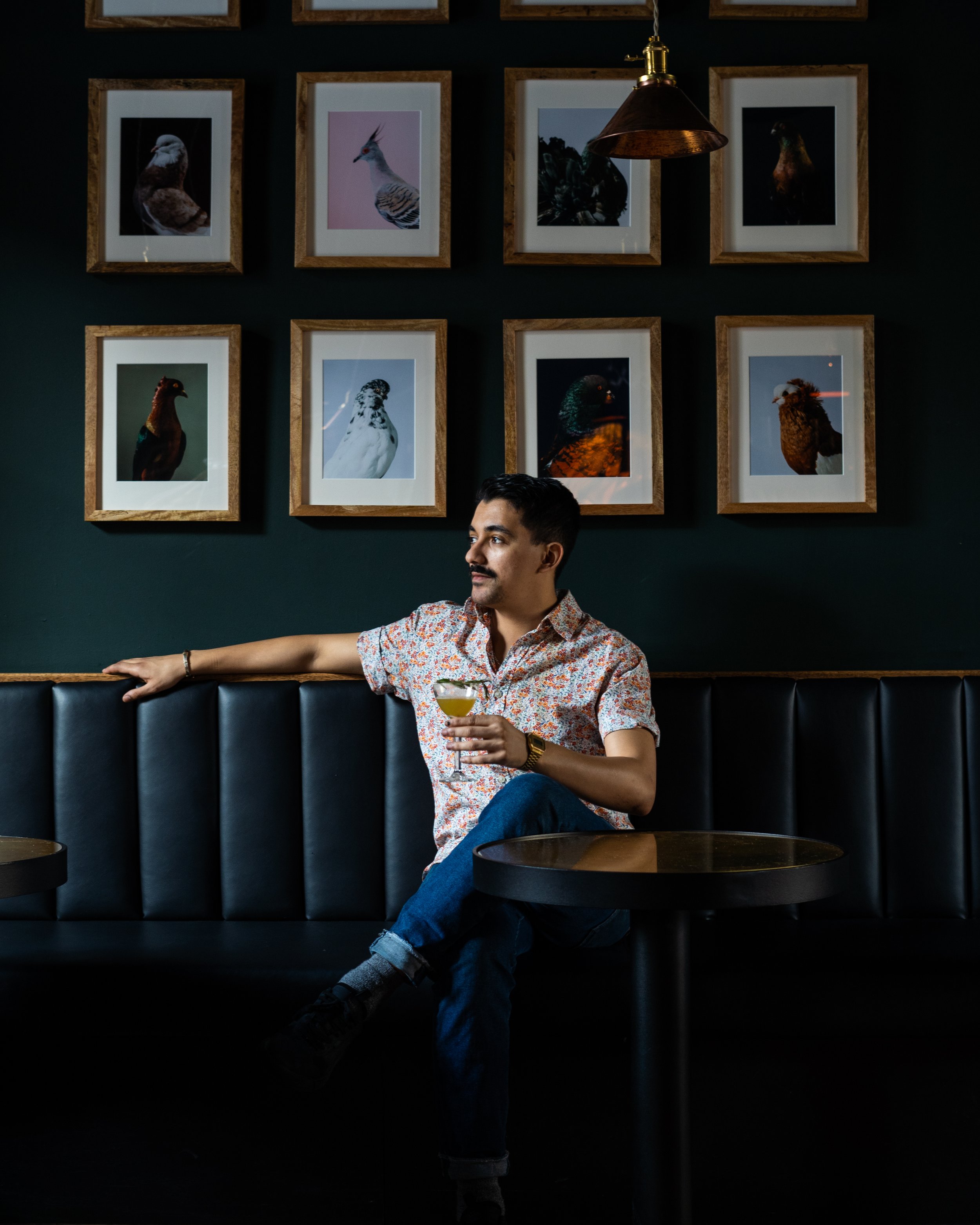 A man wearing a colorful short-sleeve shirt and jeans is sitting at a booth at The Hyde Restaurant. Photographed by Gumption Studio, Ottawa food photographer.