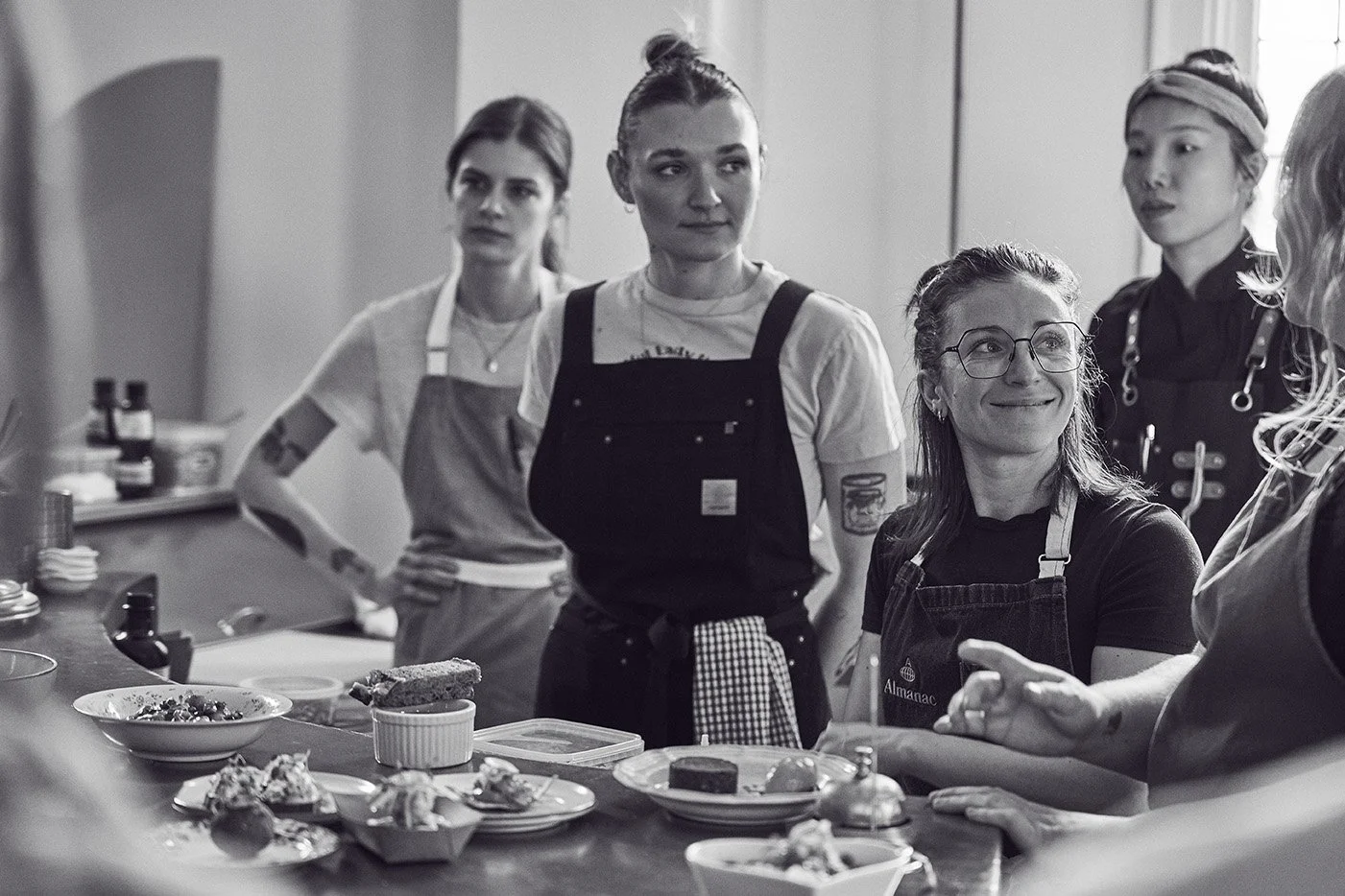 The Girl Dinner Chefs at Parlour some wearing aprons, surrounded by dishes and ingredients. Photographed by Gumption Studio, Ottawa event photographer.