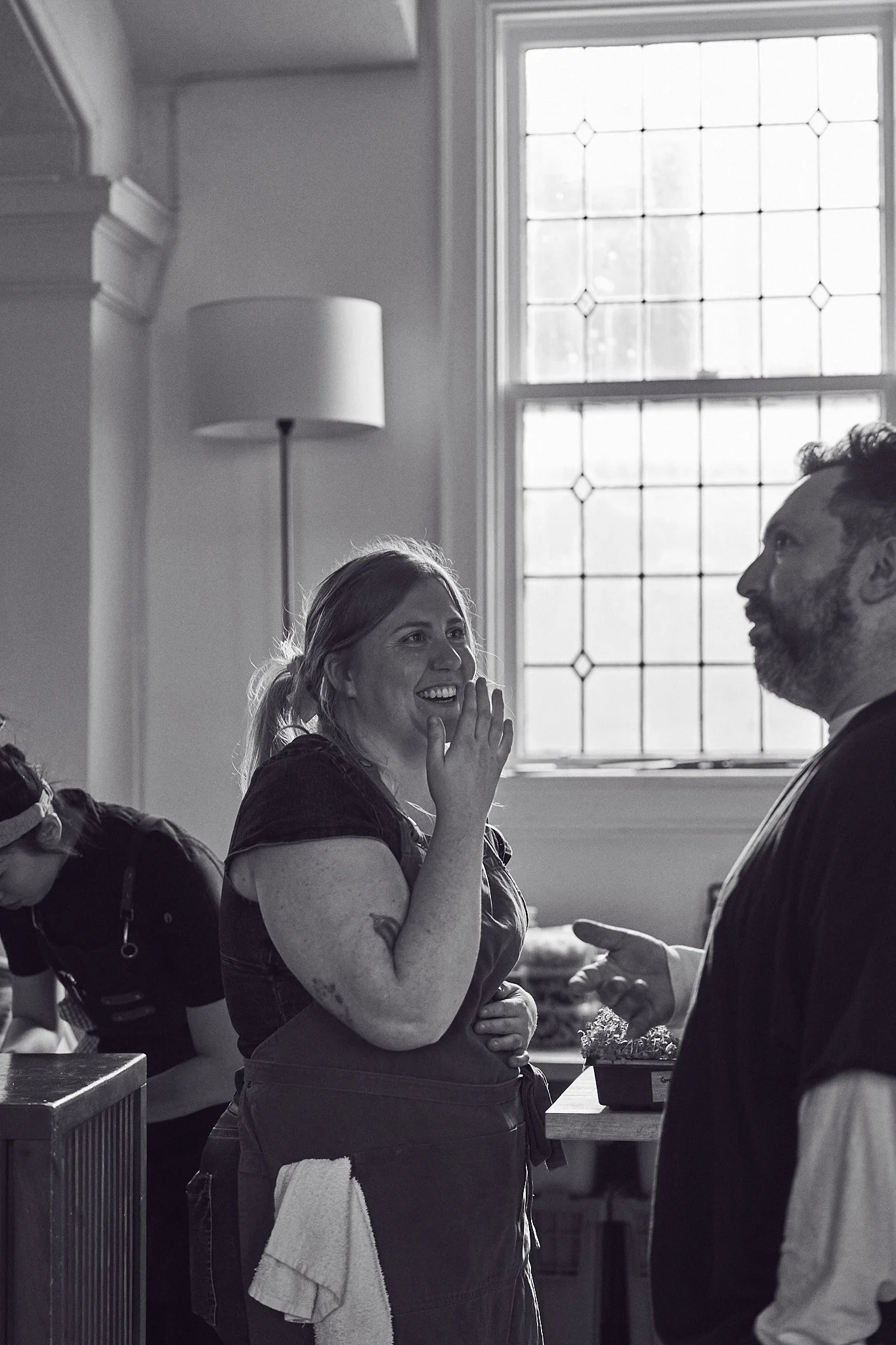 Kali Fawcett is smiling and talking to a Zachary Resnick. They are at Girl Dinner at Parlour with a large window in the background, with several other people partially visible. Photographed by Gumption Studio, Ottawa event photographer.
