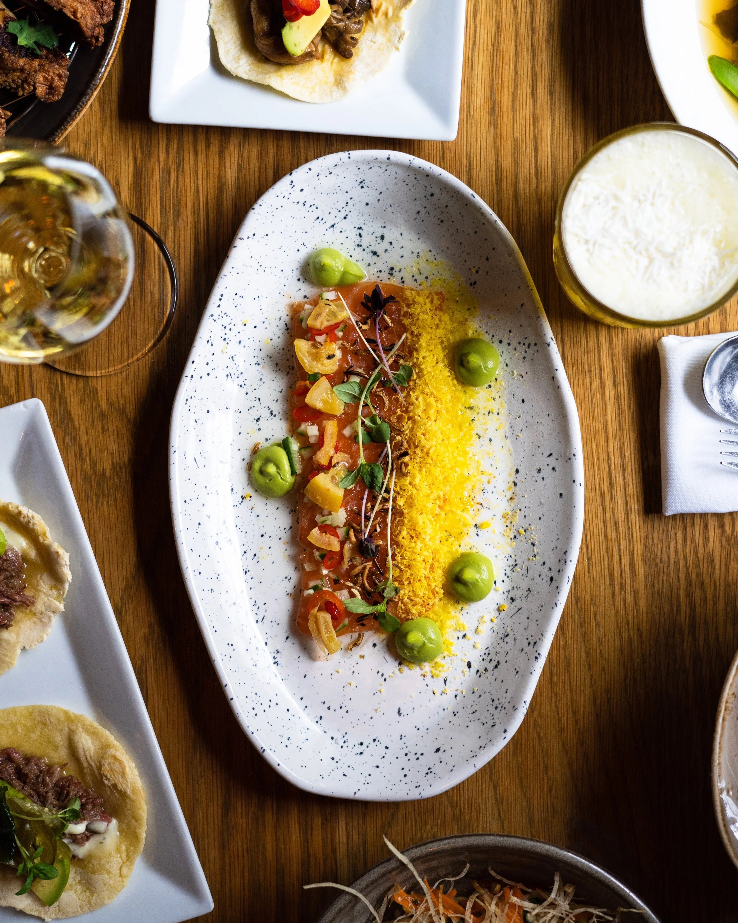 A tuna crudo fro Sidedoor Restaurant on a white plate and wood table. Photographed by Gumption Studio, Ottawa food photographer.