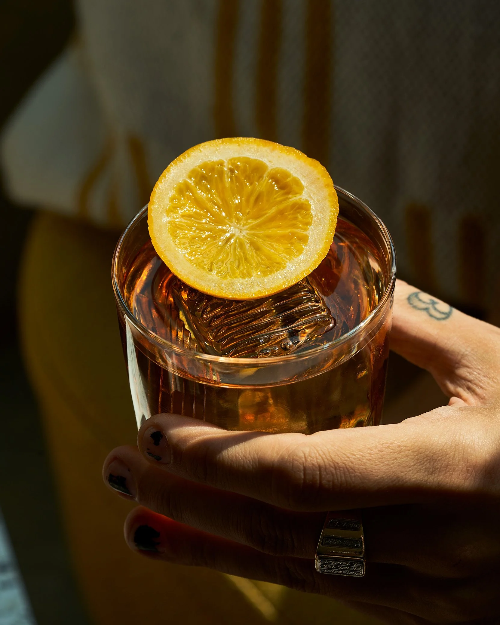 A hand with dark nail polish holding a old fashion cocktail from Split Tree. Photographed by Gumption Studio, Ottawa cocktail photographer. 