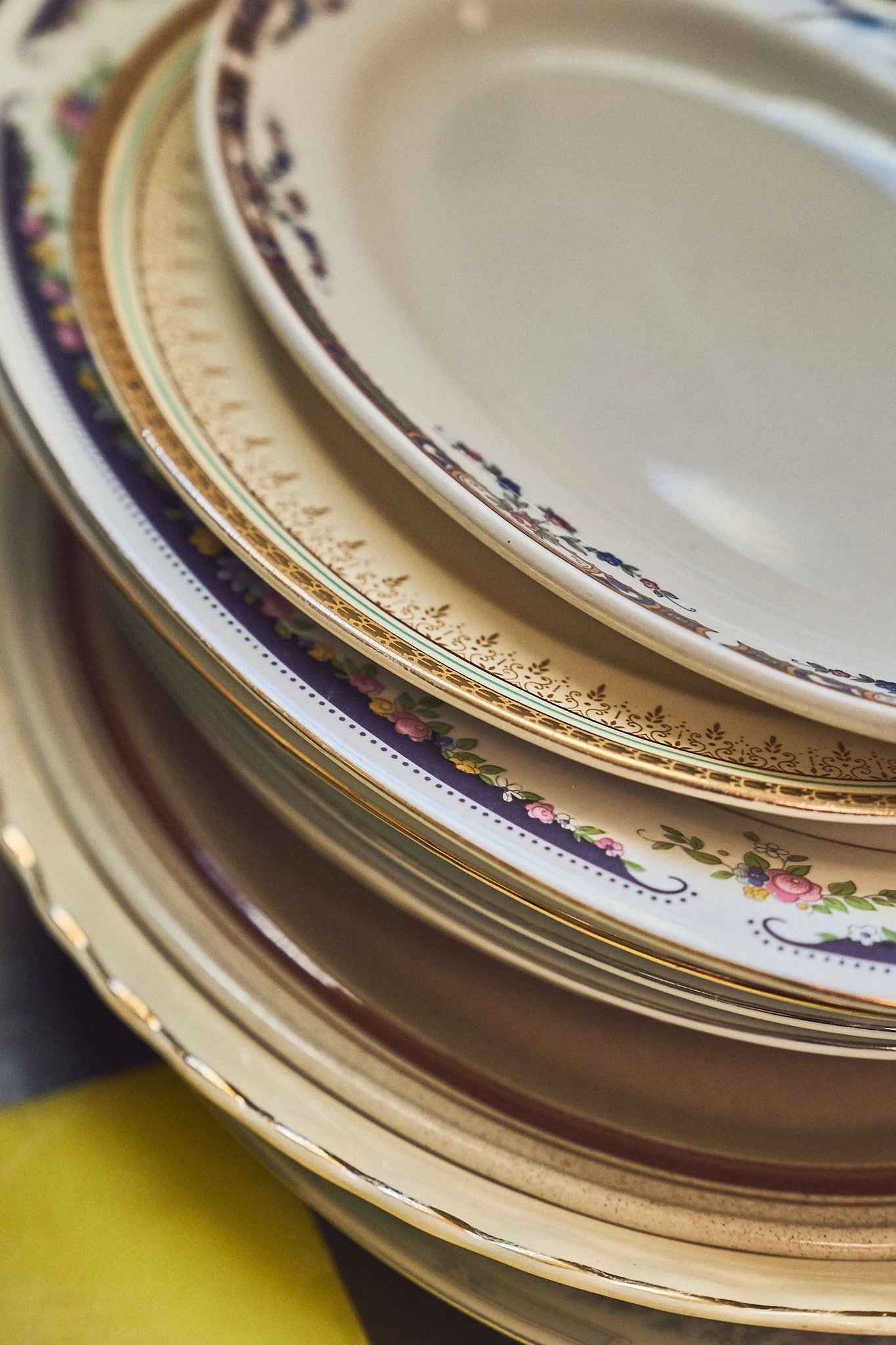 Close-up image of stacked decorative plates with floral patterns and gold trim, seen from the side. Photographed by Gumption Studio, Ottawa event photographer.