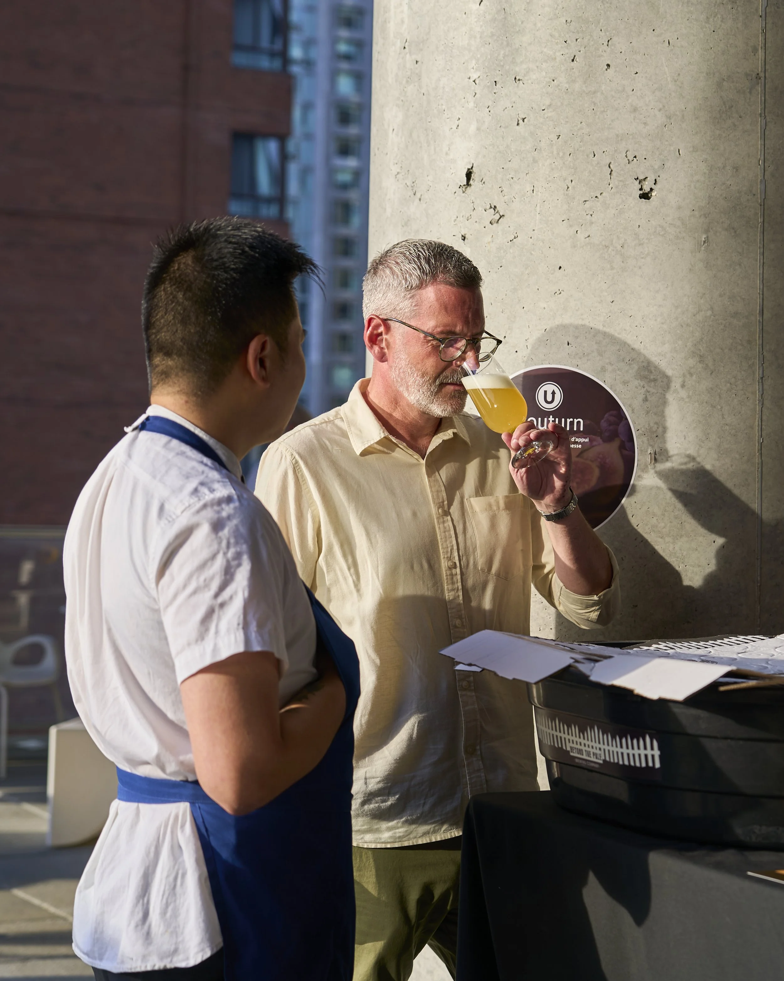 Chef Tu Le and Shannon Marshall holding a glass of beer, at Harvest: A Feast of Fall. Photographed by Gumption Studio, Ottawa event photographer.