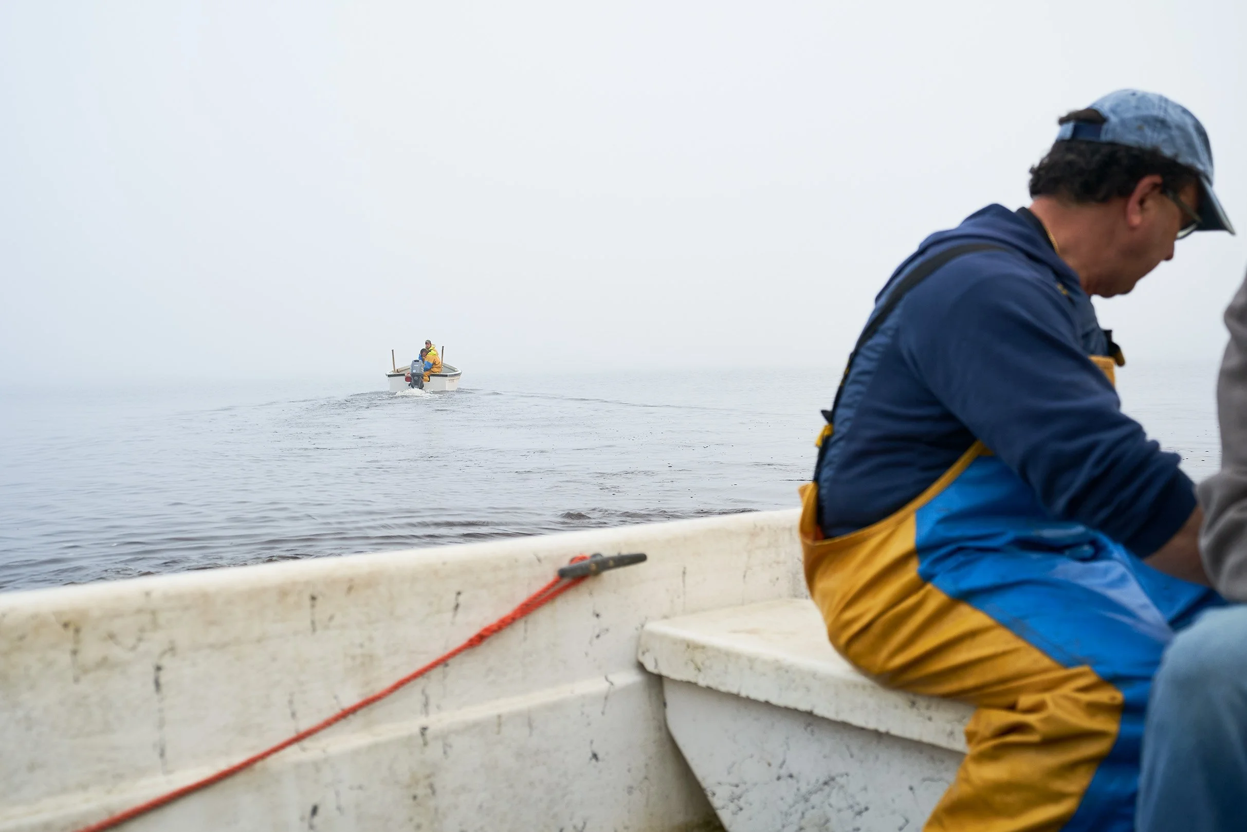  Cornel Ceapa of Acadian Sturgeon and Caviar in a boat on the water, with an overcast sky, wearing outdoor gear. Photographed for the Perch Cookbook by Gumption Studio, Ottawa Cookbook photographer.