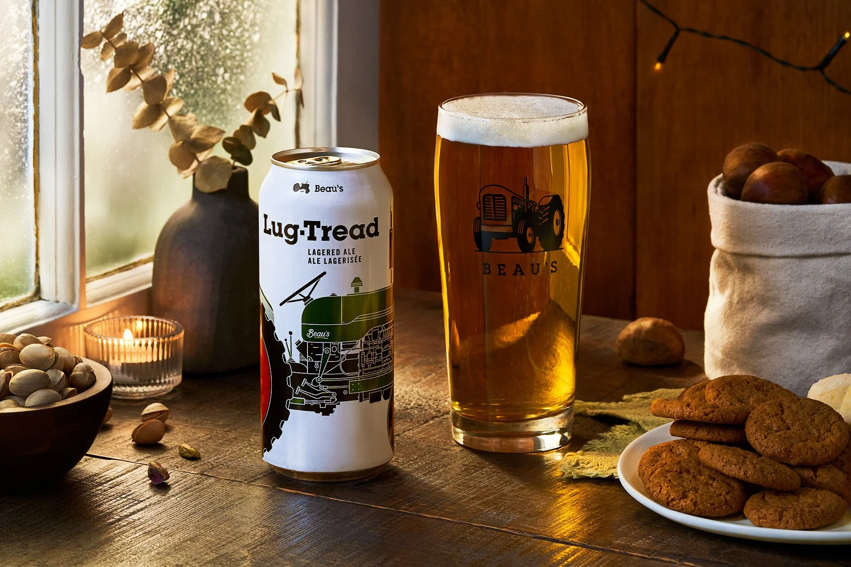 A can of Beau's Lug-Tread a pint glass filled with beer on a rustic wooden table. Taken for their Christmas Advertisement Photographed by Gumption Studio, Ottawa commercial beverage photographer.