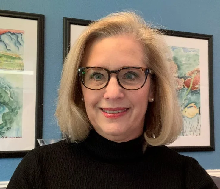 Jennifer smiles in glasses and a black turtleneck