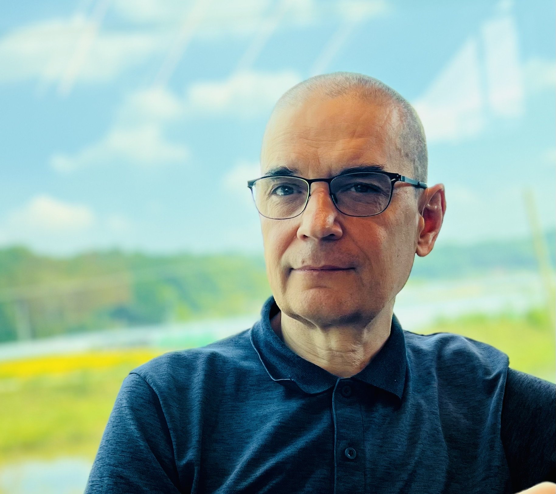 Andrzej sits in front of a nature landscape
