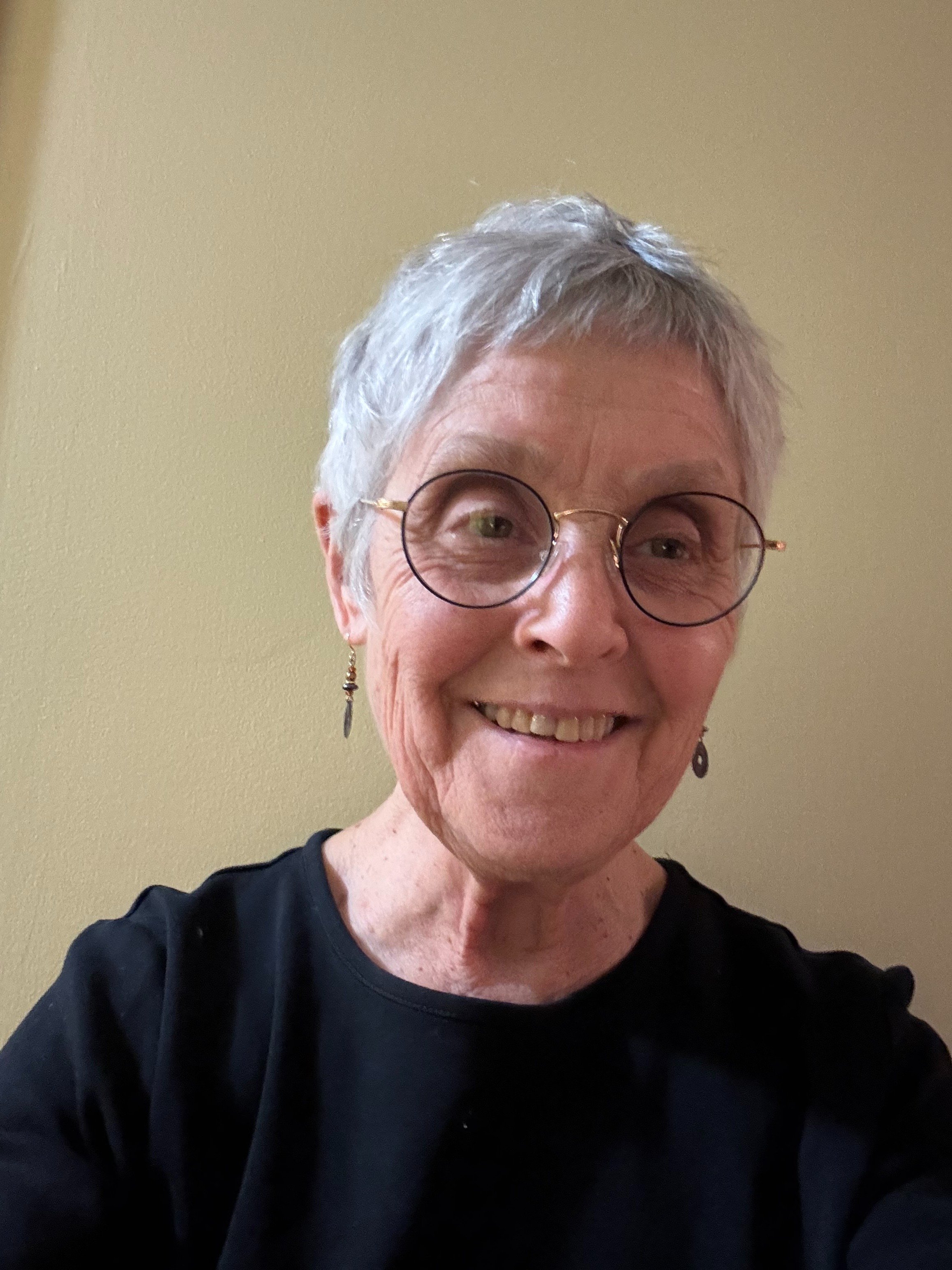 Zen Master Bon Hae smiles into the camera, wearing a black top and earrings