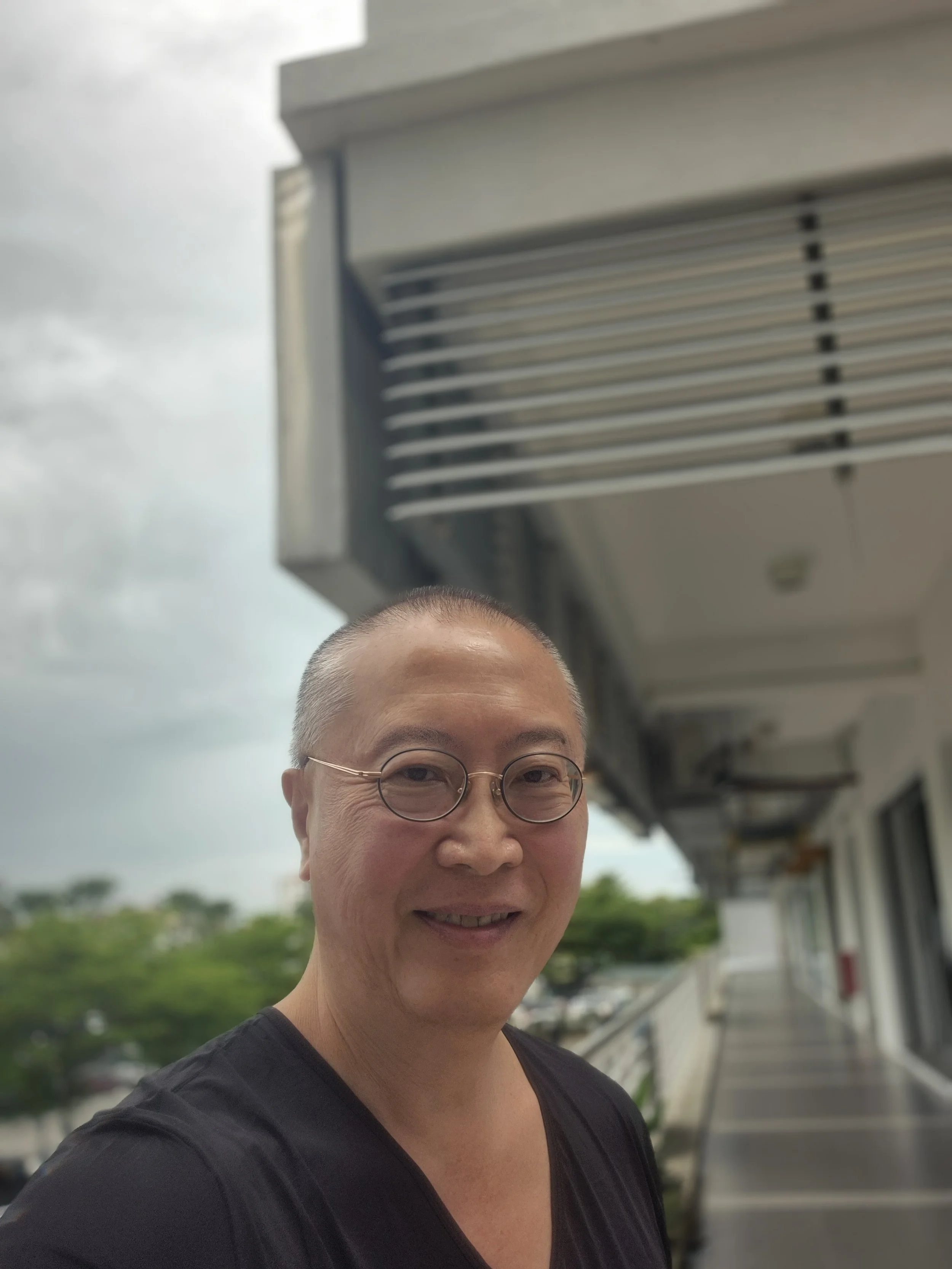 SK stands outside, wearing glasses and a black shirt