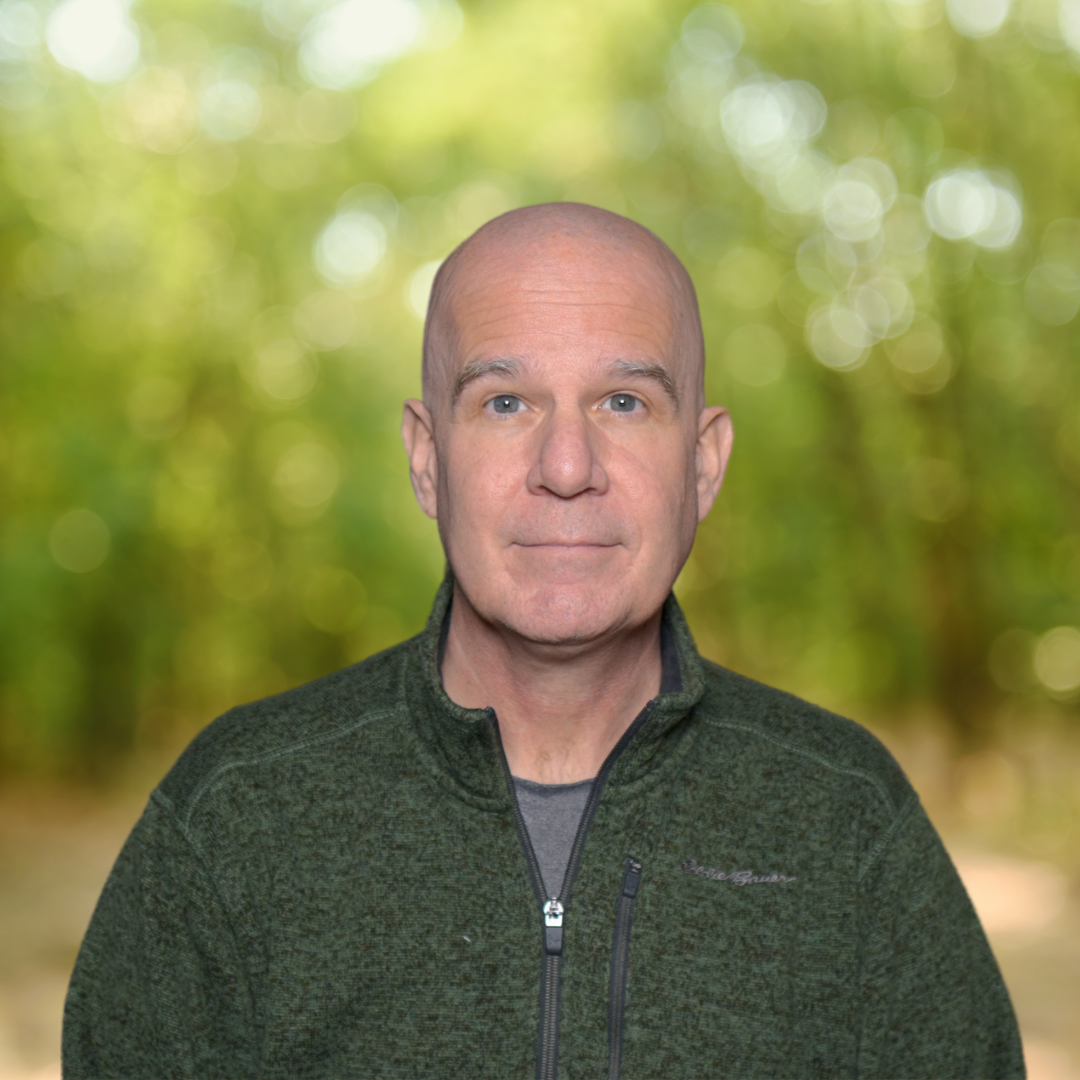 Jason stands in a green quarter-zip sweater