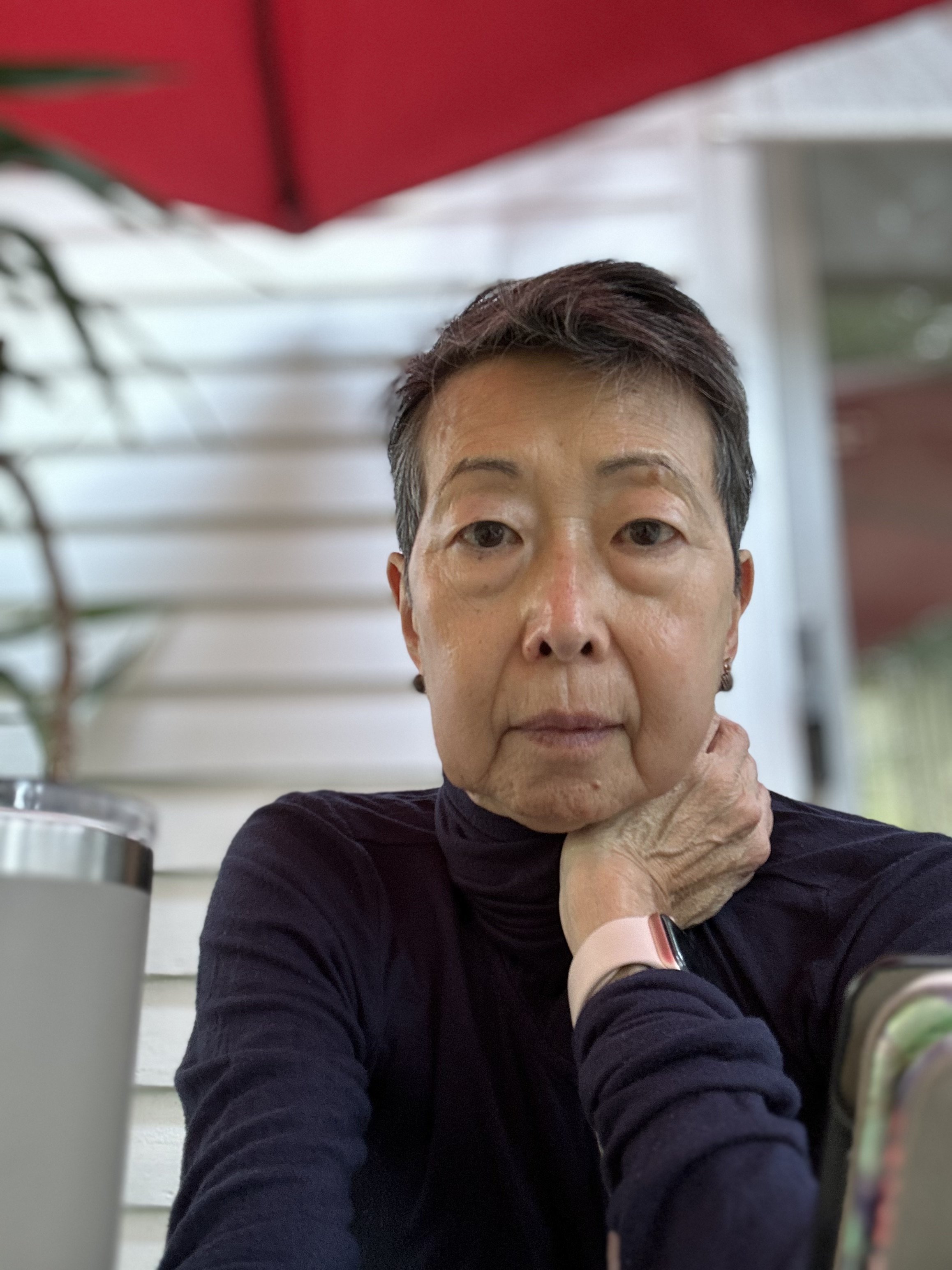 Annie sits outside in a dark shirt, leaning her neck on her hand