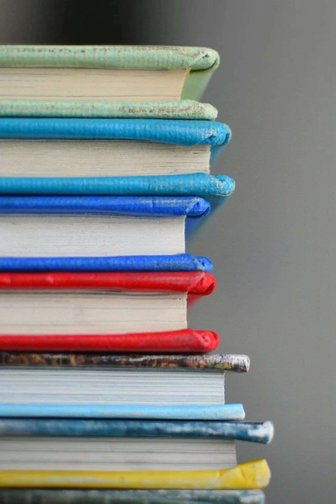 Stack of books with colorful covers, arranged vertically, with visible edges of pages on each book.