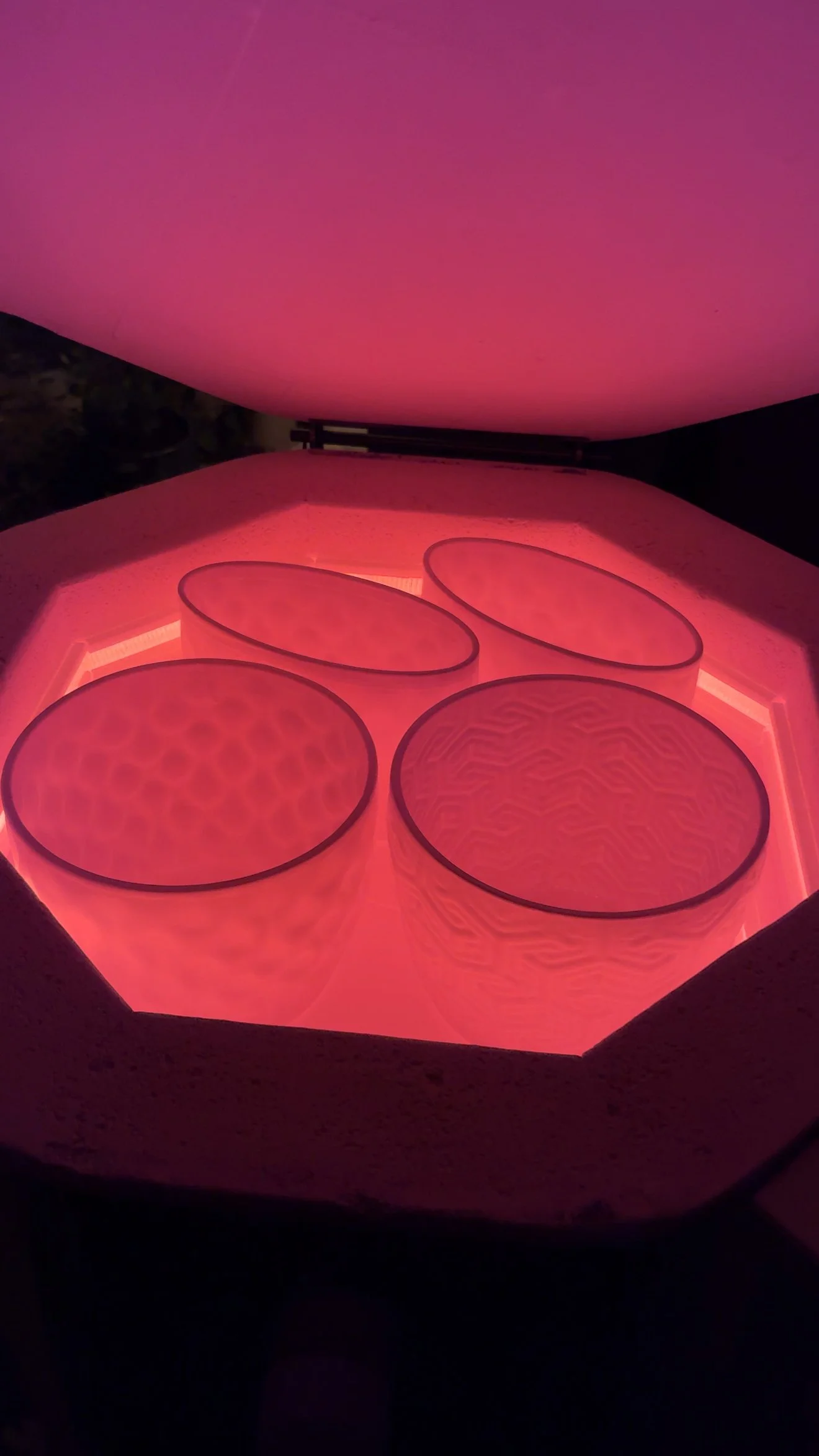 Four ceramic vases and planters with geometric patterns, glowing pink, a quick sneak peek in a kiln being fired.