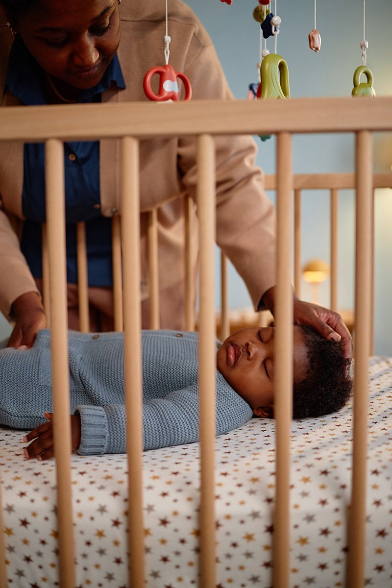 Newborn parent looks down lovingly at their baby in the crib