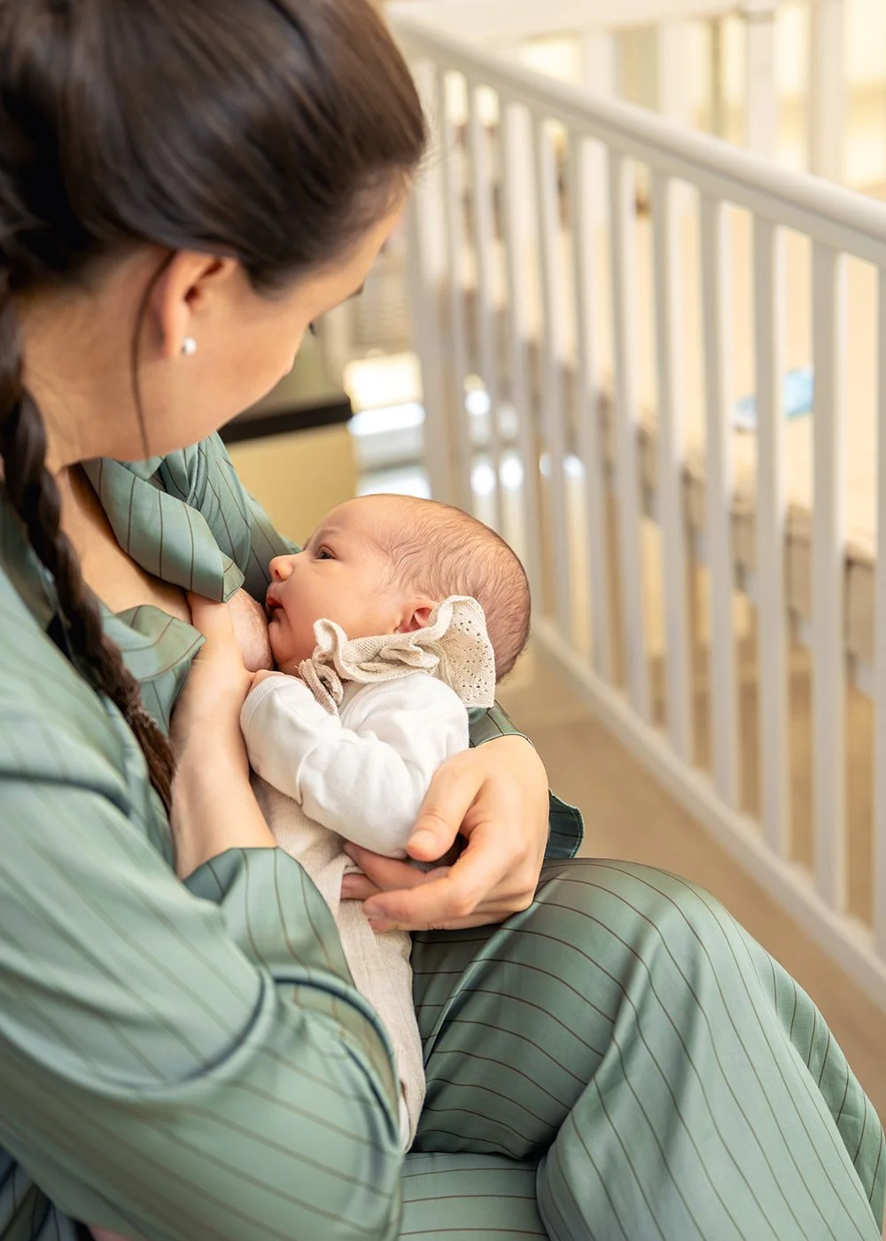 Parent sitting in a nursery chair, breastfeeding an infant in their lap