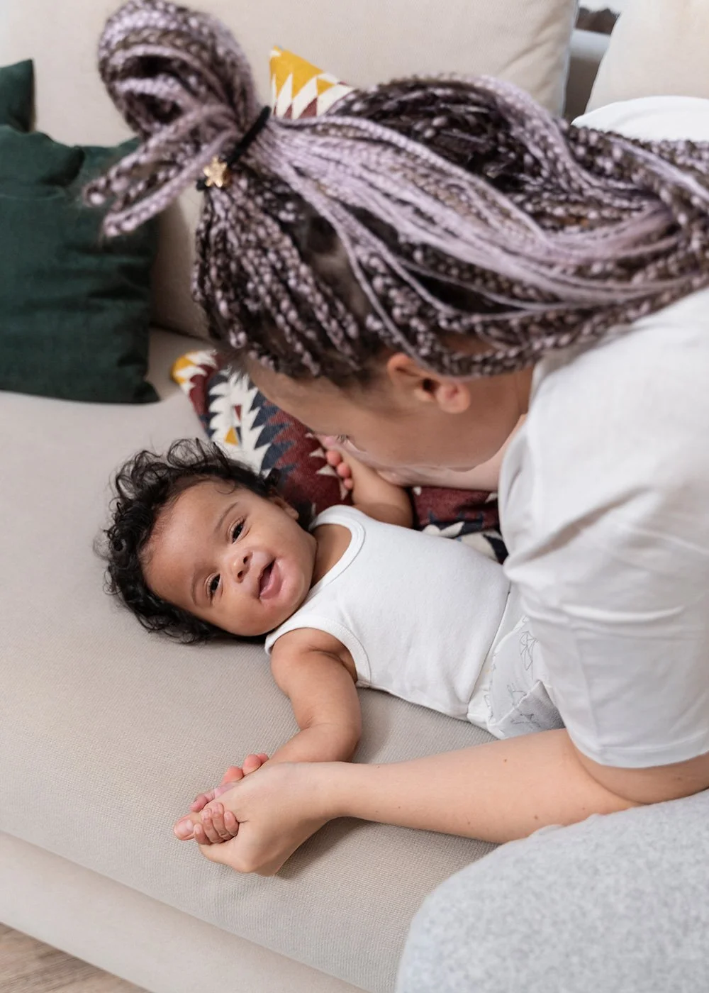 Baby resting on couch with his mom looking over him
